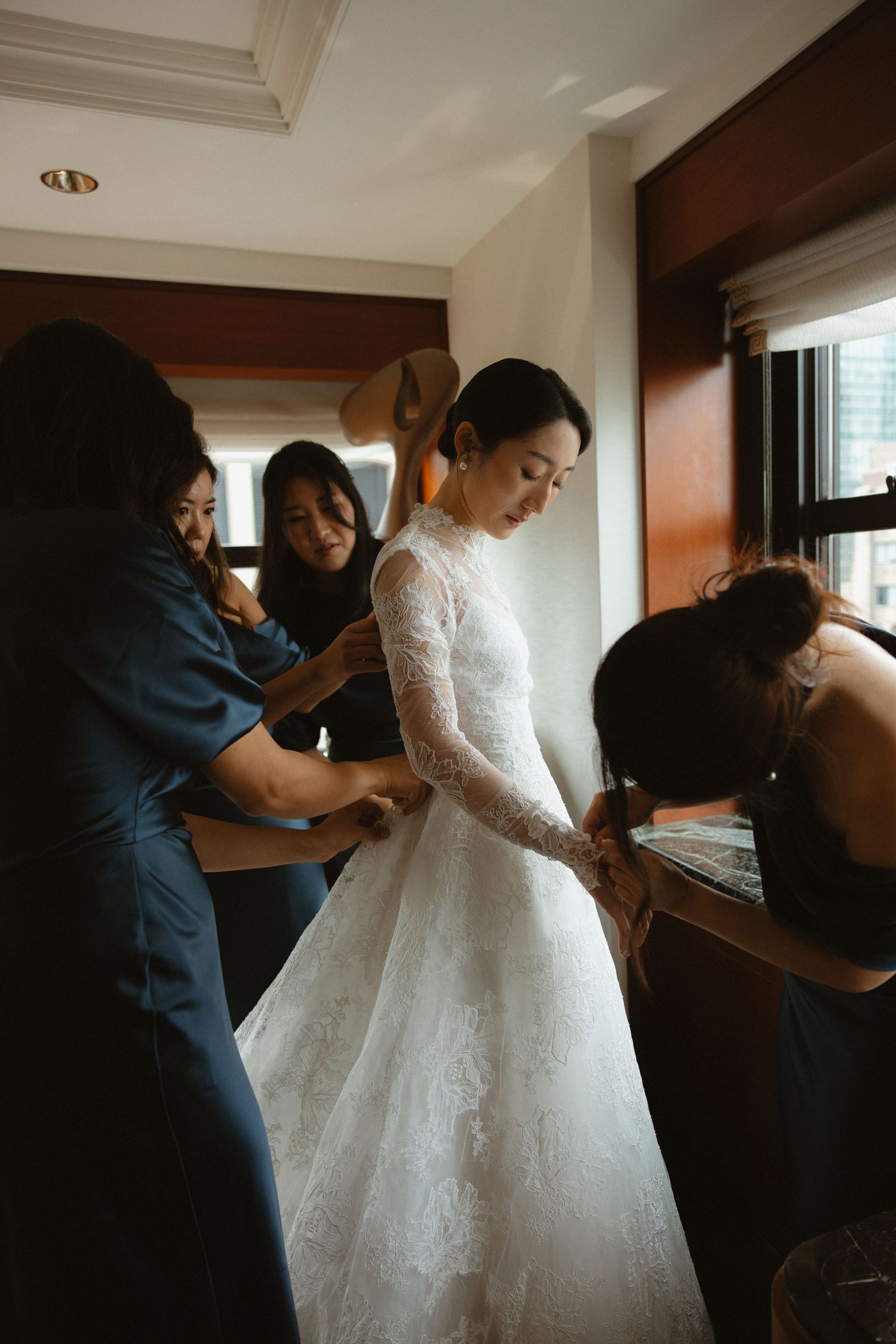 A wedding dress fitting session showing final adjustments being made to an elegant white ballgown.