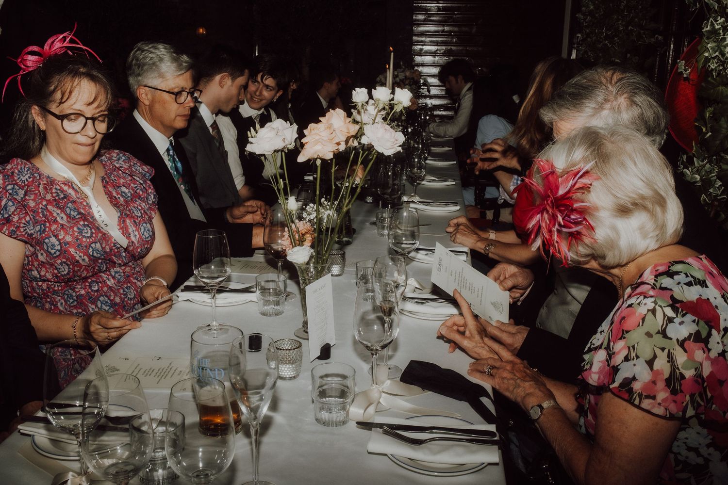 Wedding reception guests enjoying dinner and conversation at decorated tables.