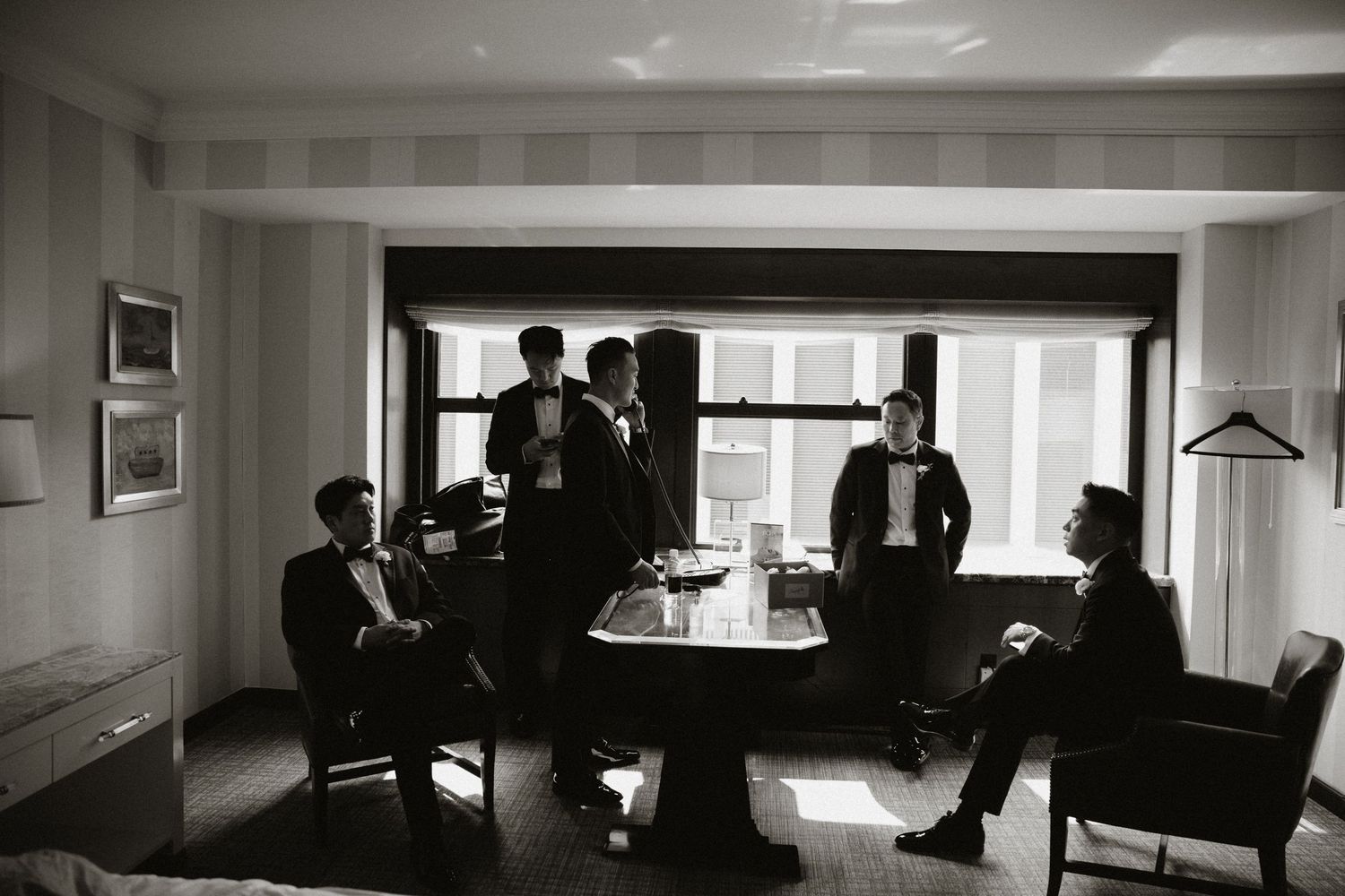 A moody black and white panoramic sequence of silhouettes in a hotel room.