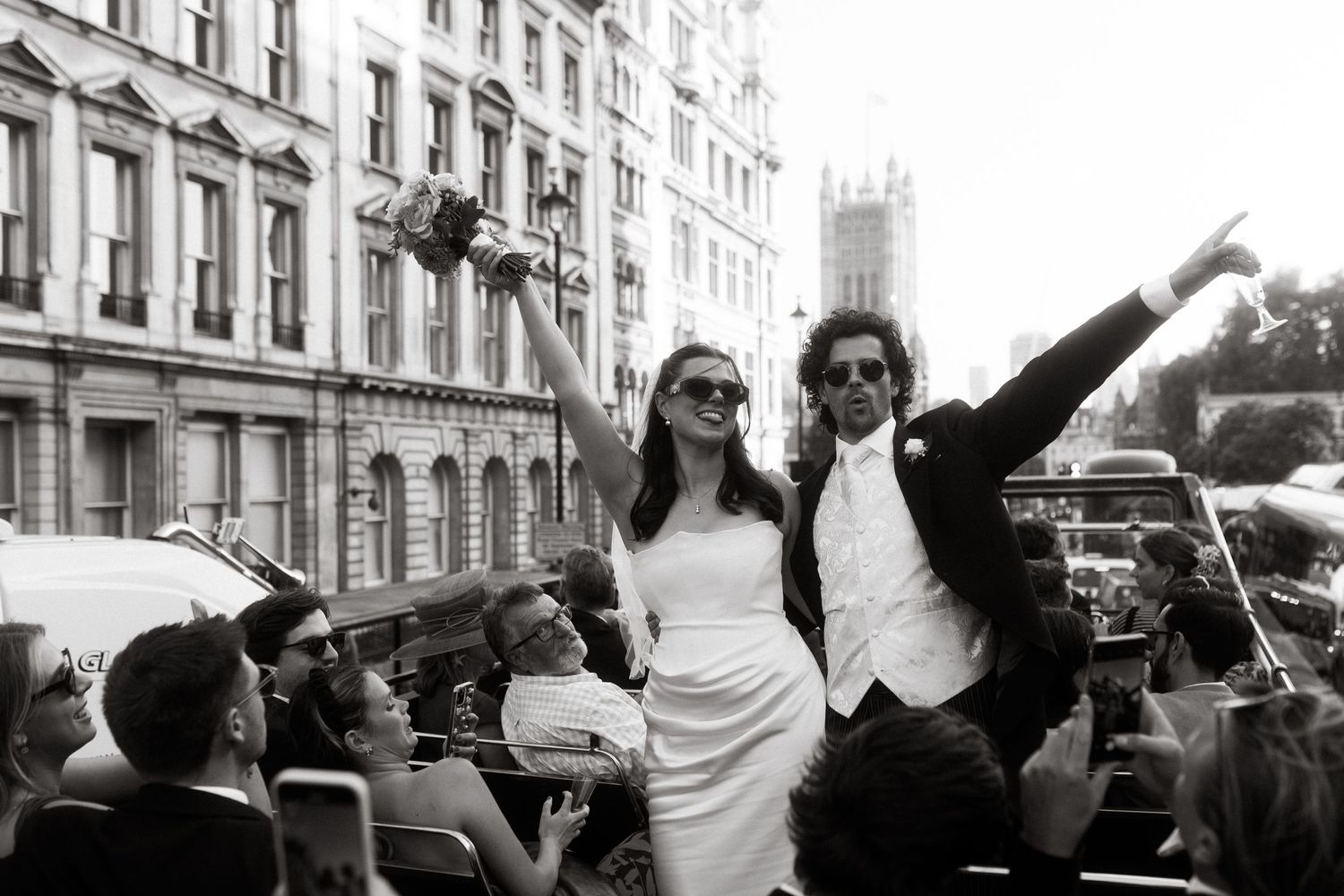A joyful celebration scene with newlyweds surrounded by cheering crowds on a city street.