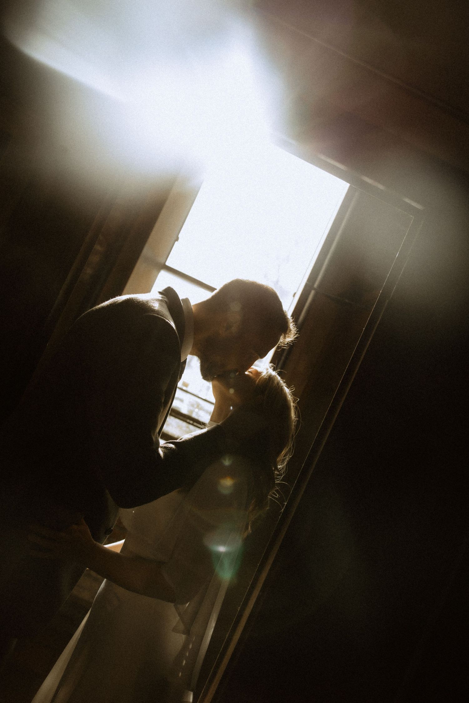 Silhouetted figures in an intimate moment against bright backlighting creating a dramatic atmosphere.