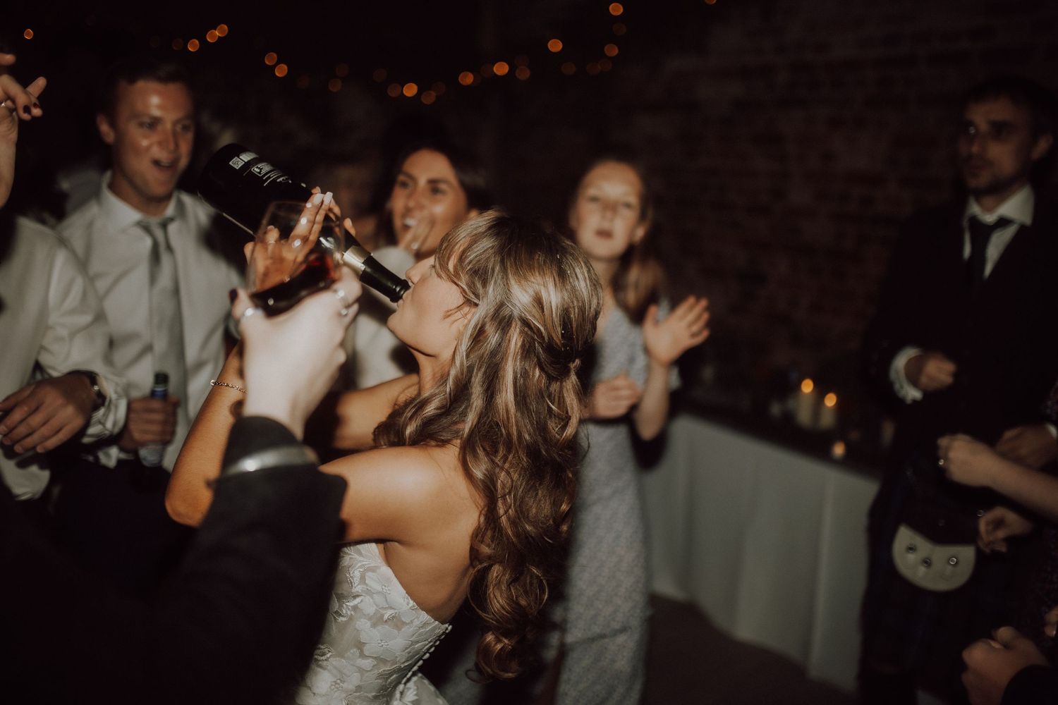 Guests celebrating at a dimly lit wedding reception with festive atmosphere.