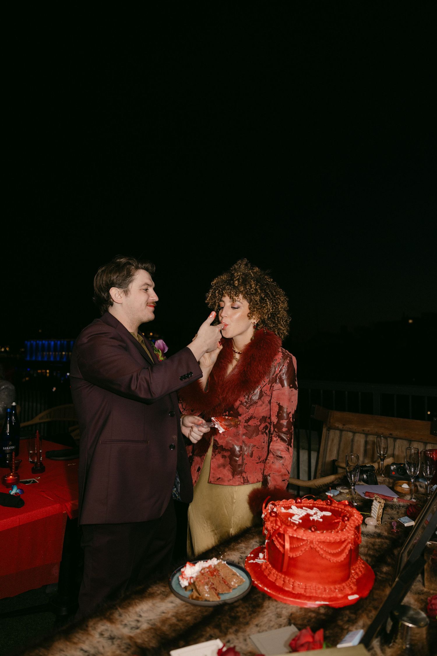 Wedding cake cutting sequence at night with red lighting and dark ambiance.