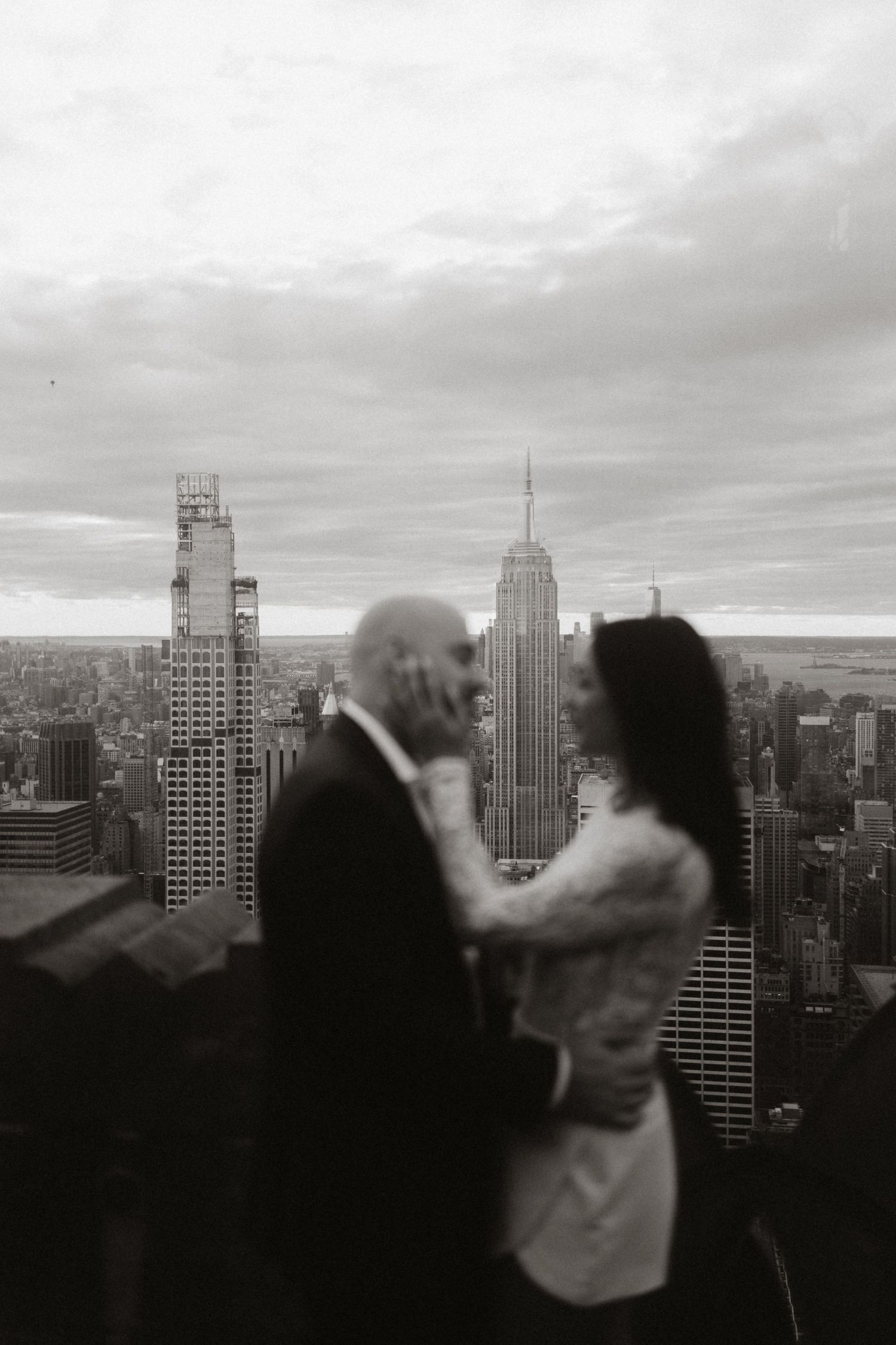 A romantic black and white cityscape moment with the Empire State Building visible in the background.