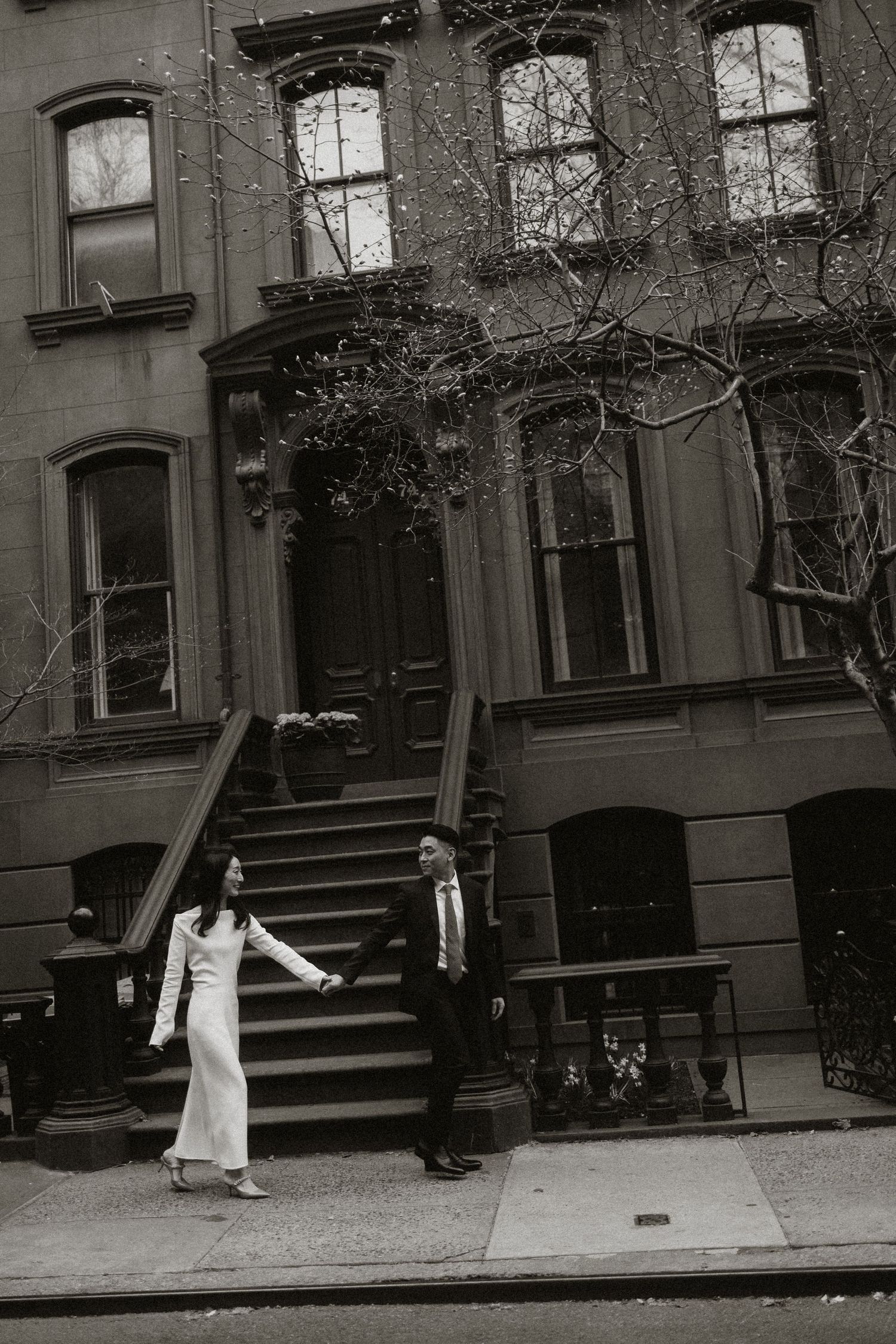 Black and white photo on steps of classic New York brownstone building.