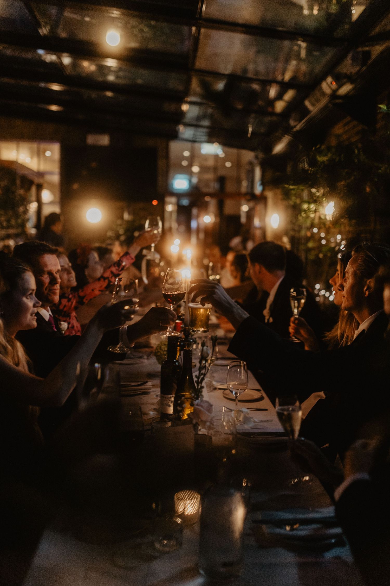 Candlelit reception venue with guests dining in a warm, intimate atmosphere.