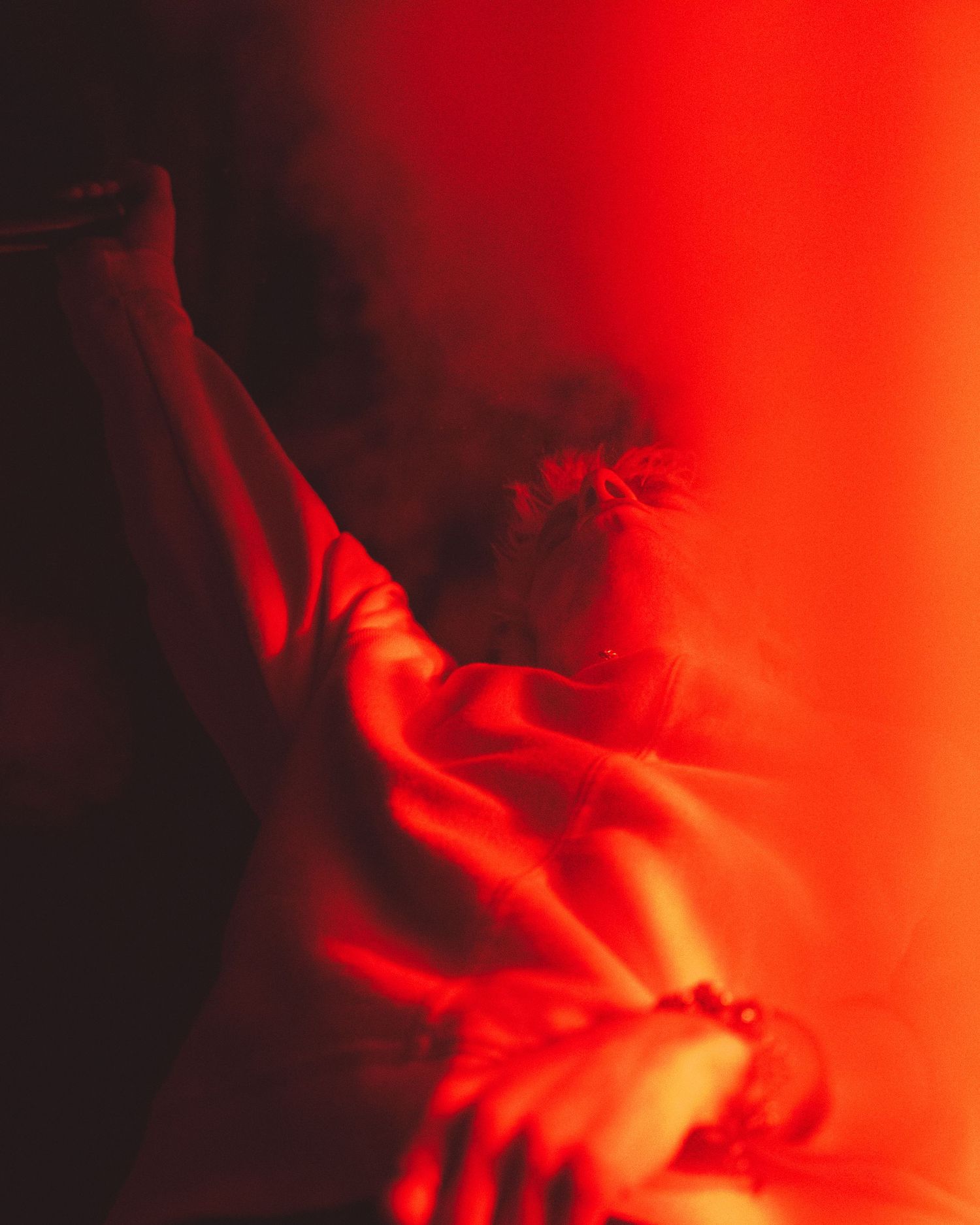 Dramatic red-lit concert performance with silhouetted figures creating an intense atmospheric mood.
