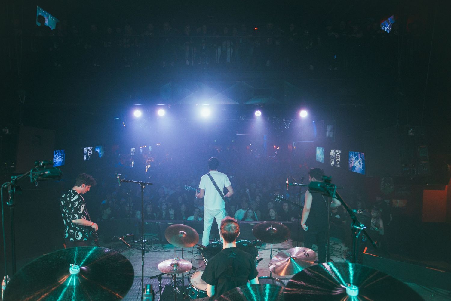 Concert performers on stage with dramatic blue and teal lighting effects.
