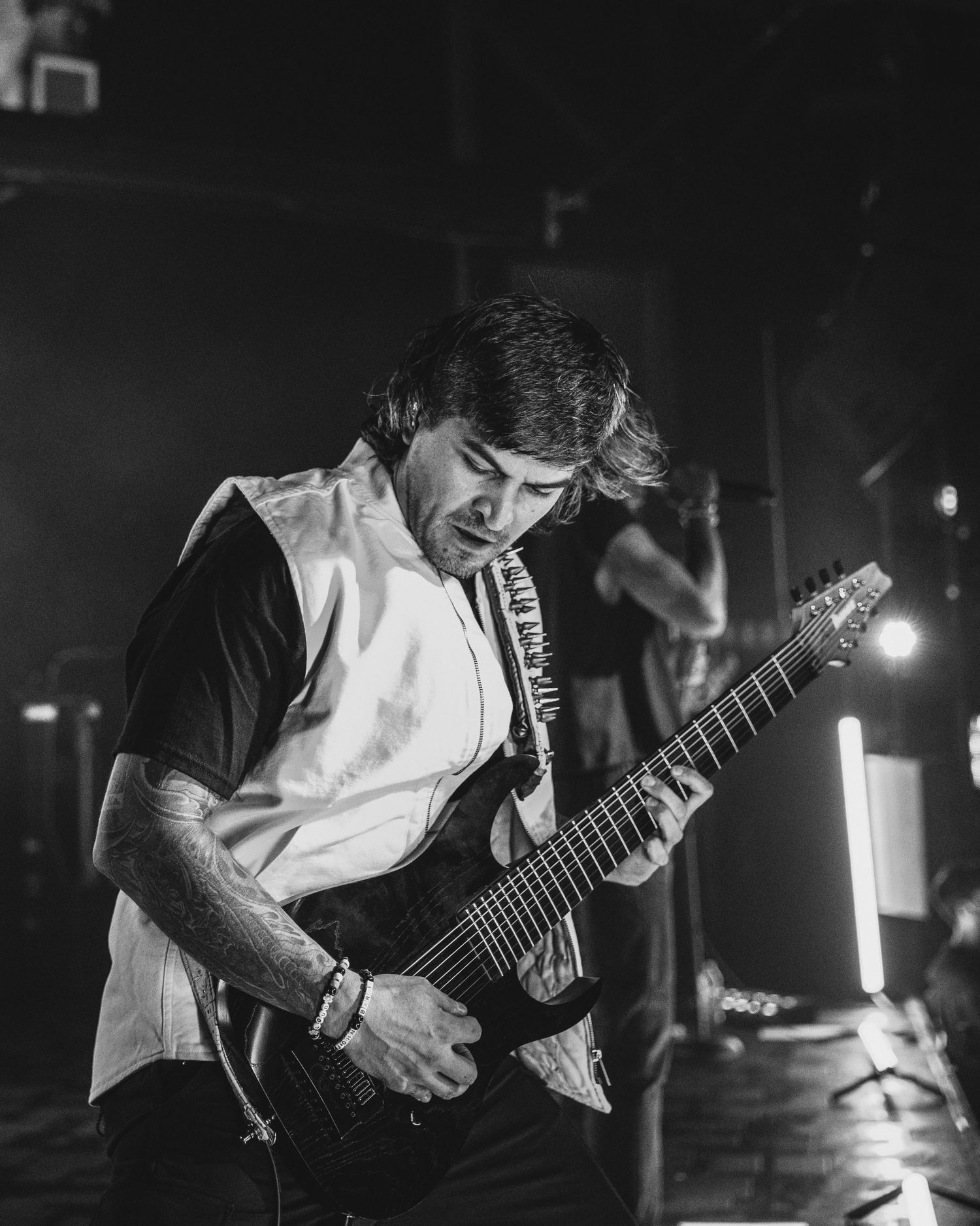 Black and white photos show a musician performing with an electric guitar on stage in dramatic lighting.