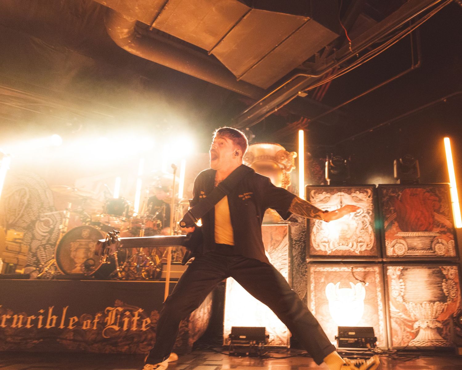 A dramatic stage performance with silhouettes against bright backlighting during a rock concert.