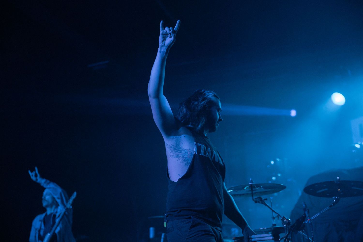 Concert performers on stage bathed in dramatic blue lighting during a live music performance.