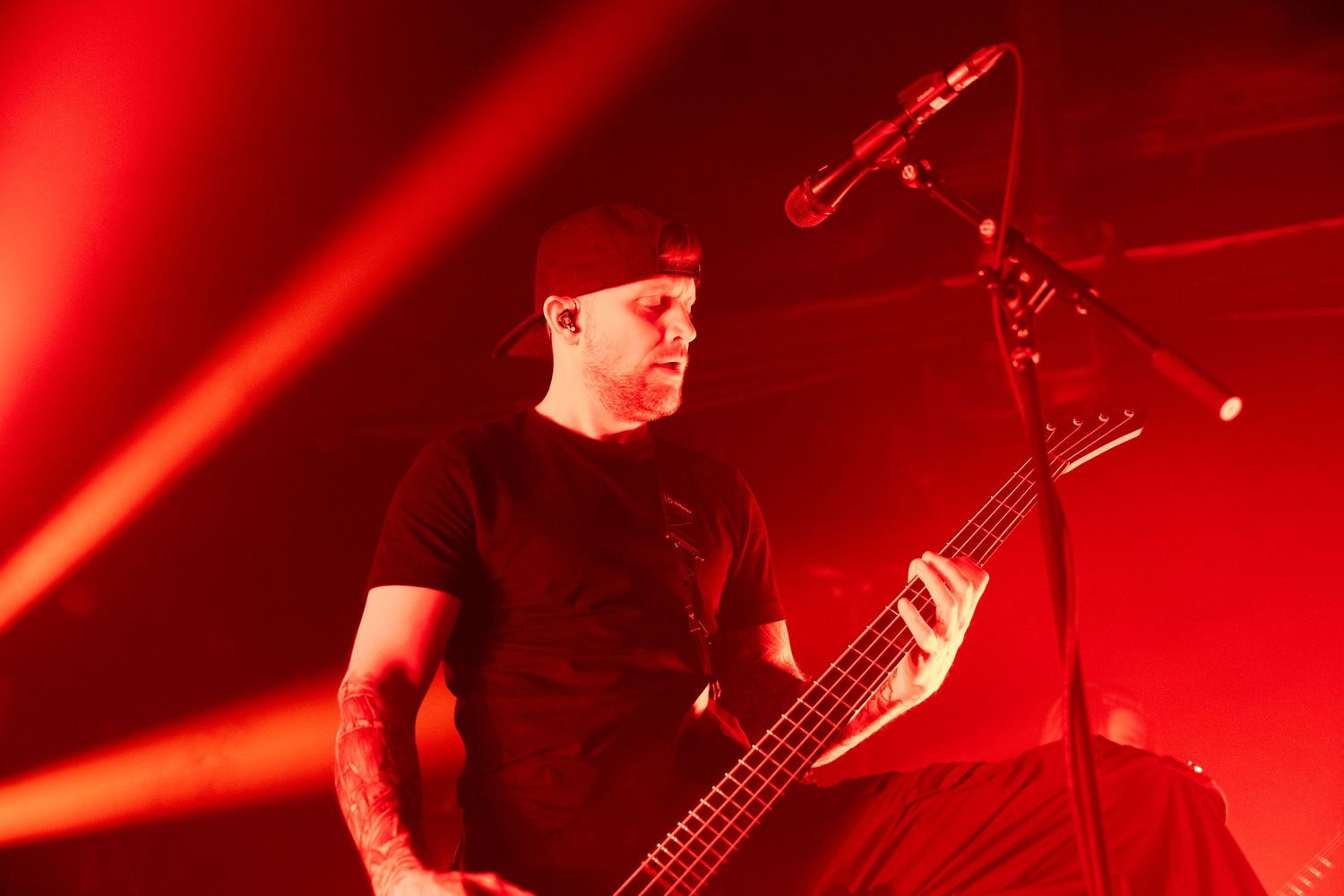 Musicians perform on stage bathed in intense red lighting creating a dramatic concert atmosphere.