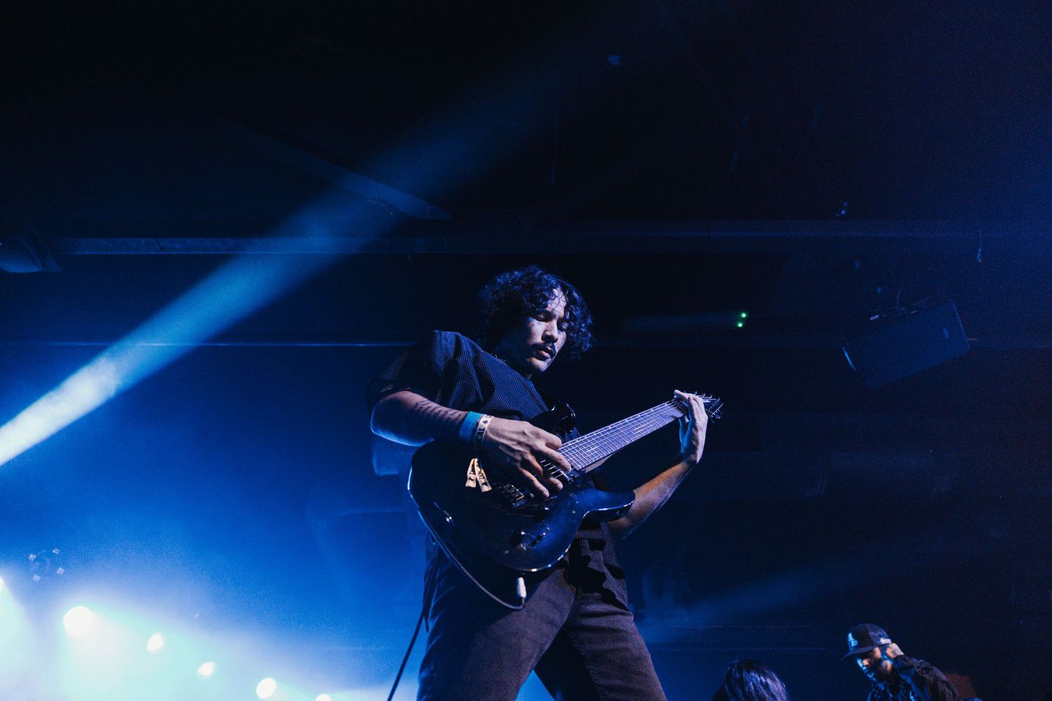 Performers in black outfits dance on stage under dramatic blue lighting during a theatrical show.