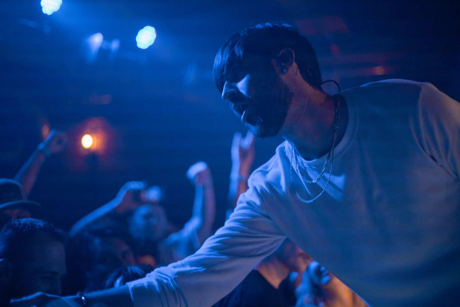 Concert performer silhouetted against blue stage lights during live show.