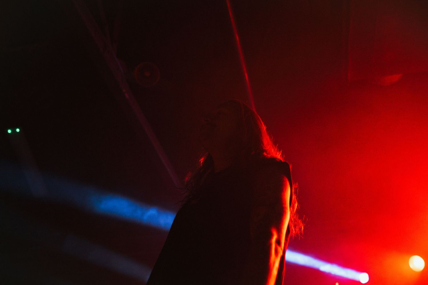 A silhouetted figure stands against dramatic red and blue stage lighting during a performance.