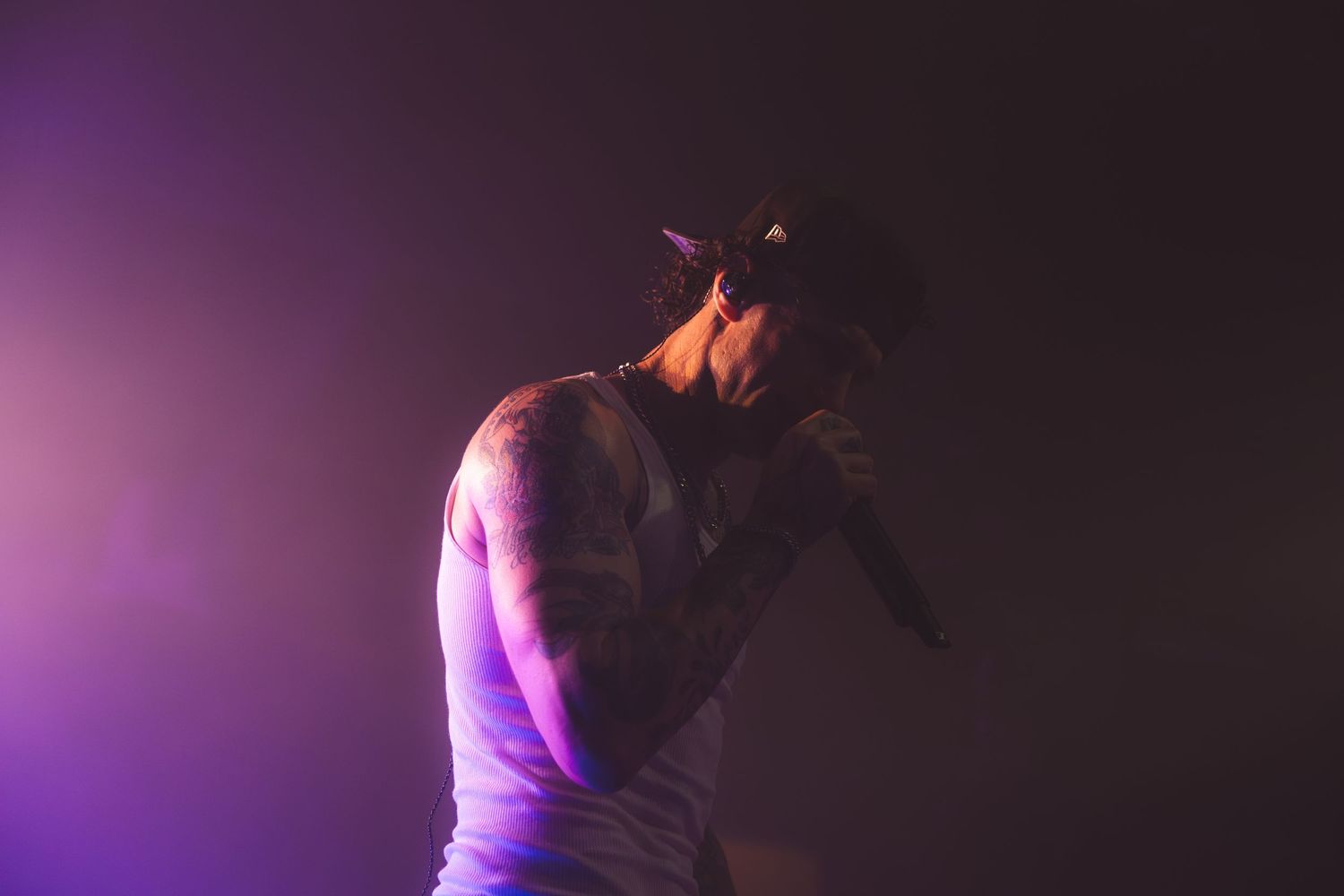 A black figure in silhouette dances dramatically against a purple illuminated background on stage.