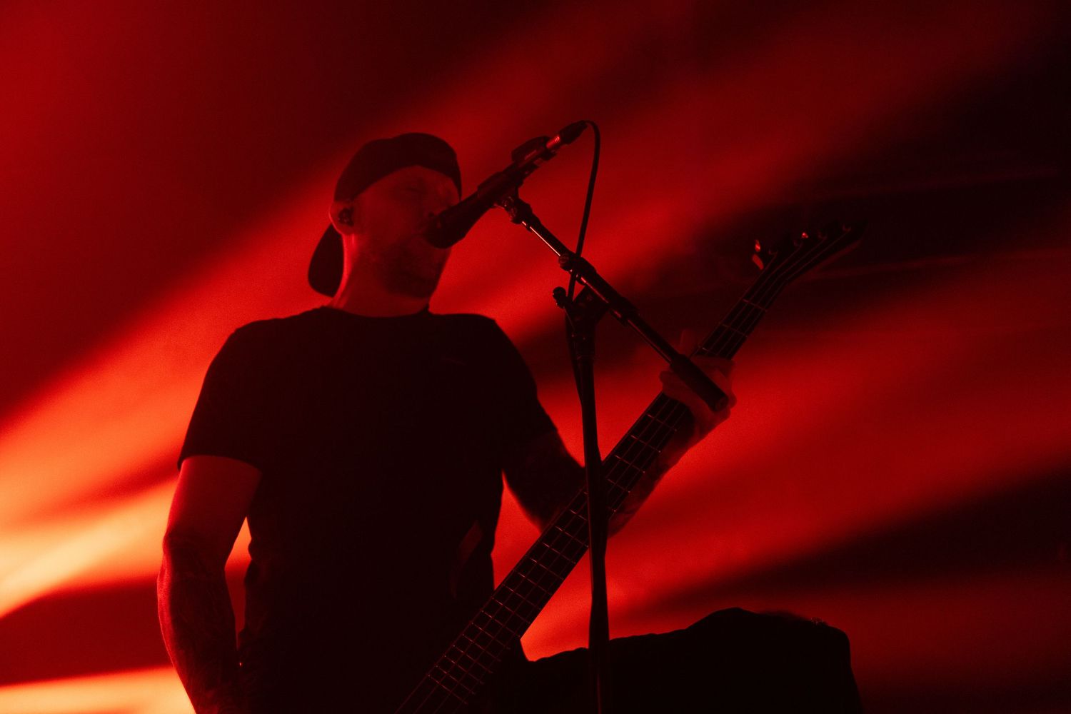 A silhouette of a vocalist performing on stage against a dramatic red lighting backdrop.