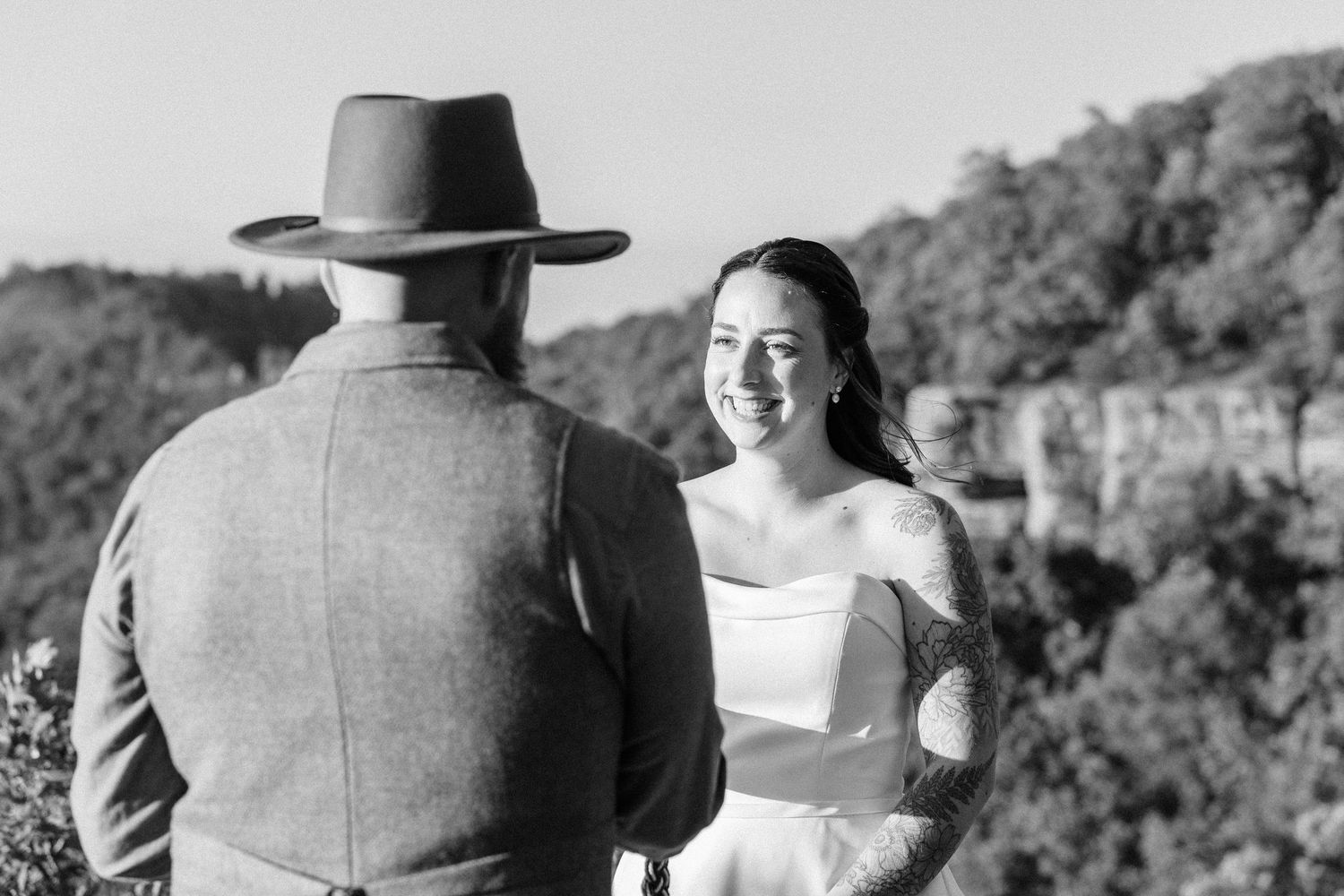 Black and white wedding ceremony moment with mountain vista in background.