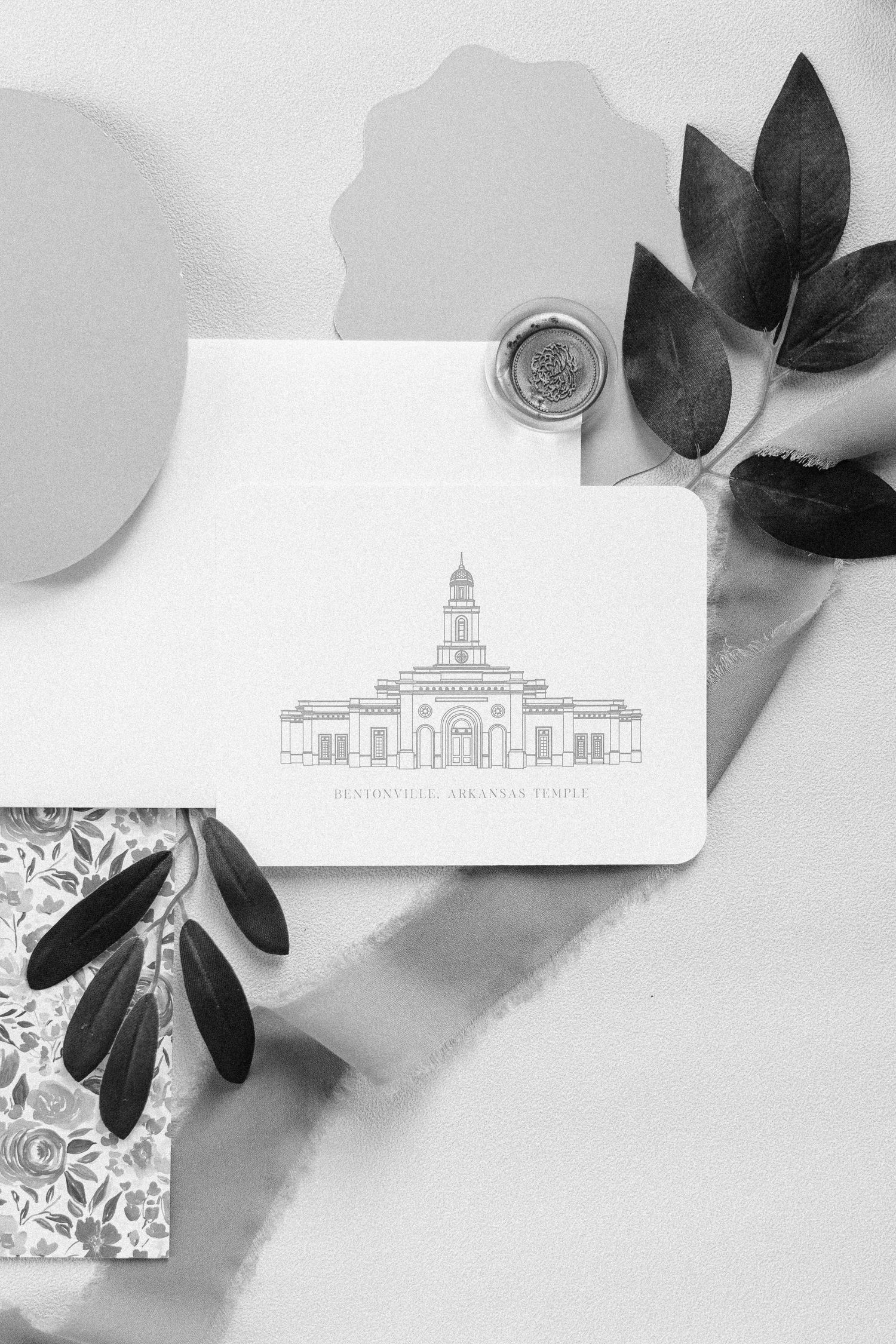 Wedding invitation suite with black floral elements and architectural sketches on white background.