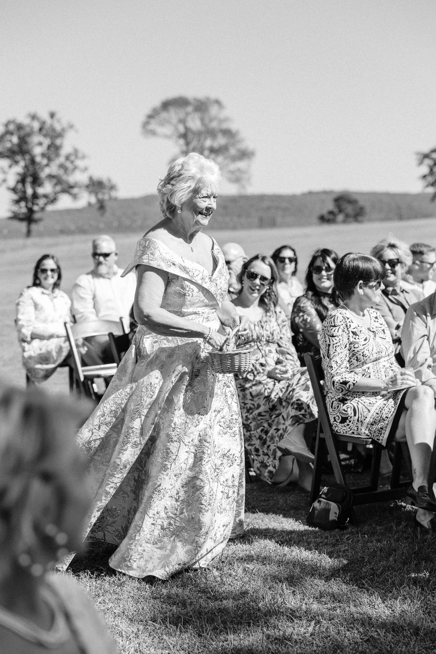Wedding guests seated outdoors on white chairs during an elegant garden ceremony.