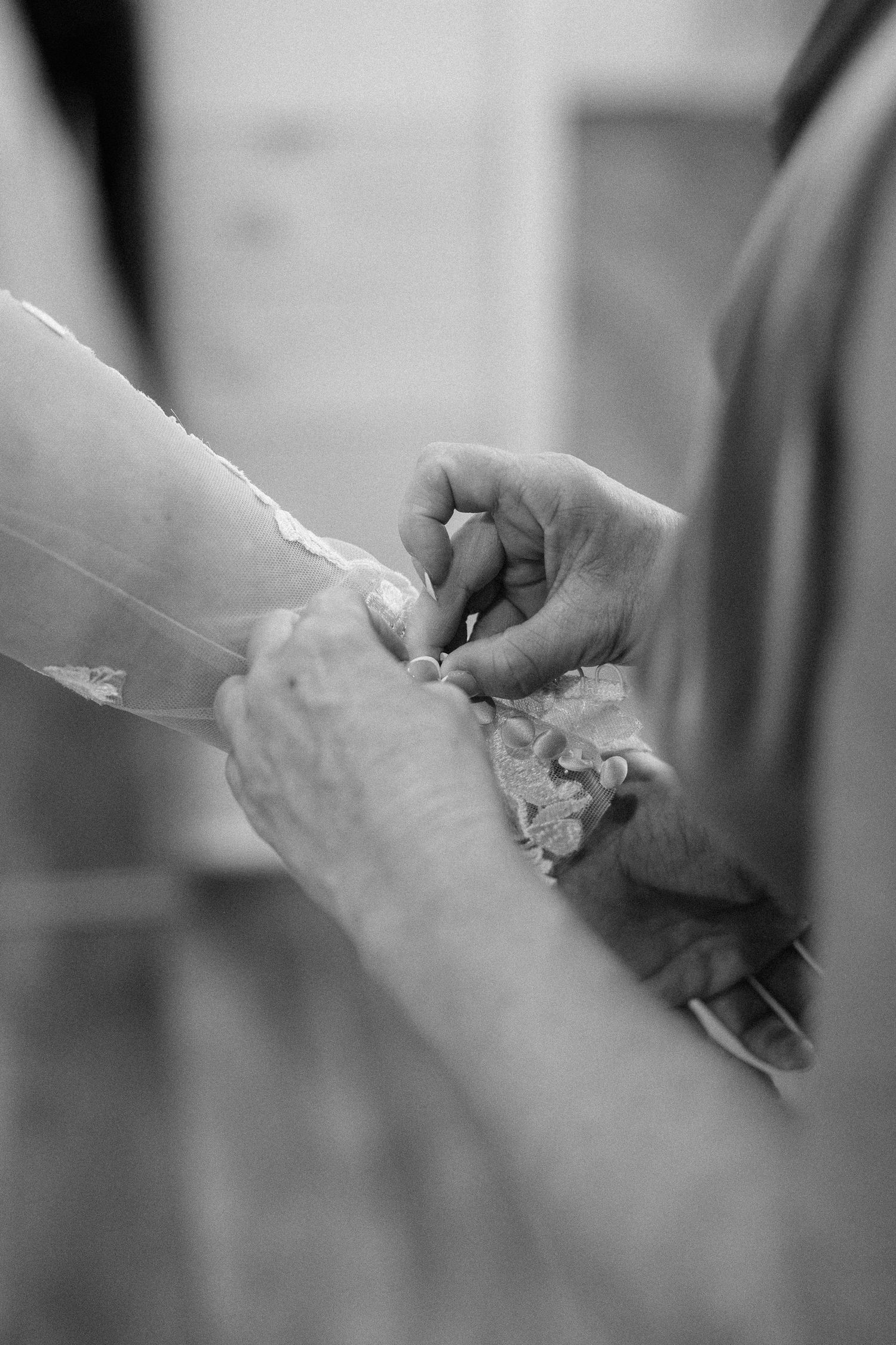 Close-up black and white shot of hands carefully handling delicate lace fabric.
