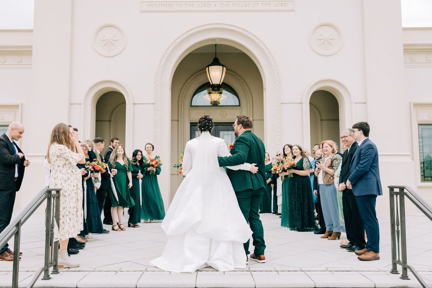 Large wedding party gathering on grand white stone steps for formal group photos.