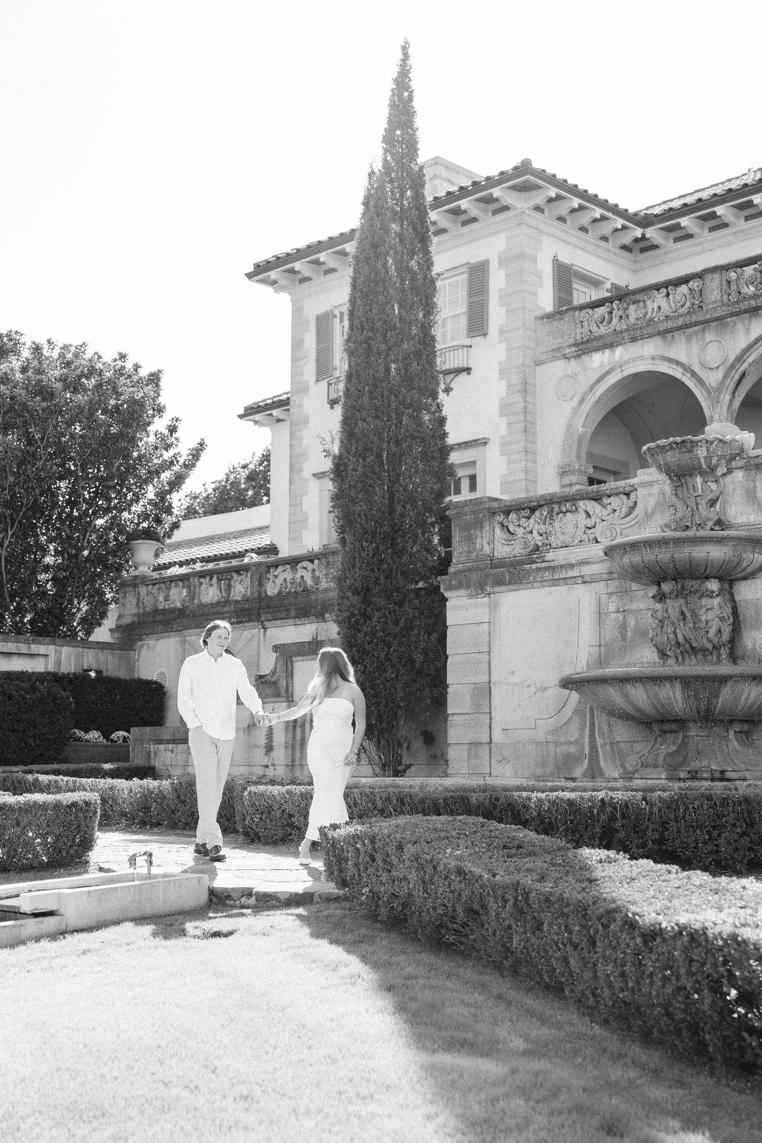 A sequence of vintage black and white photographs showing a person walking along a formal garden path near a mansion.