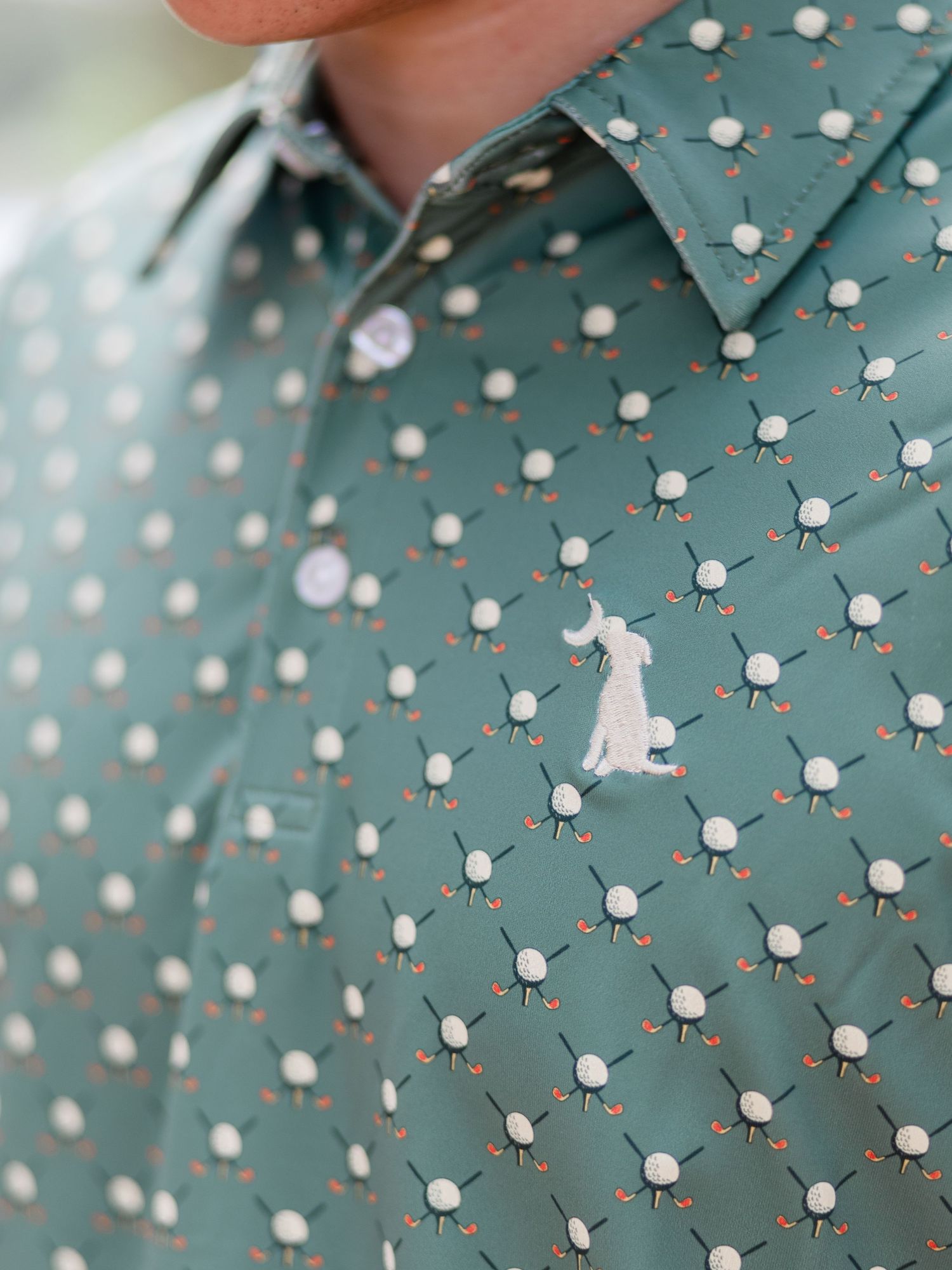 Green golf-themed button-up shirt with white ball and club print pattern, featuring embroidered logo detail.