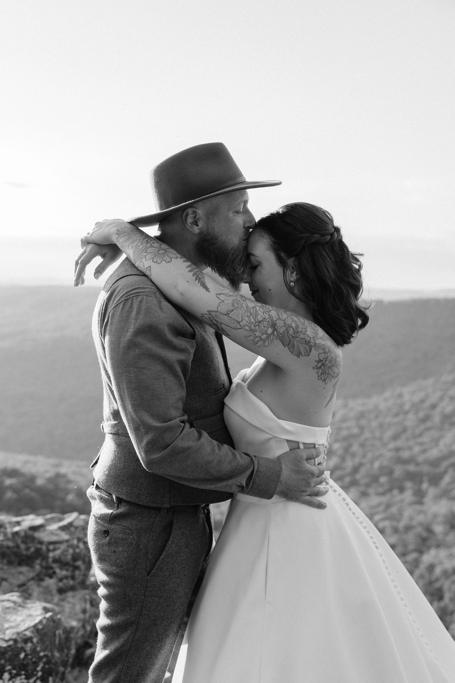 Black and white photo series showing a romantic embrace between newlyweds against a scenic mountain backdrop.
