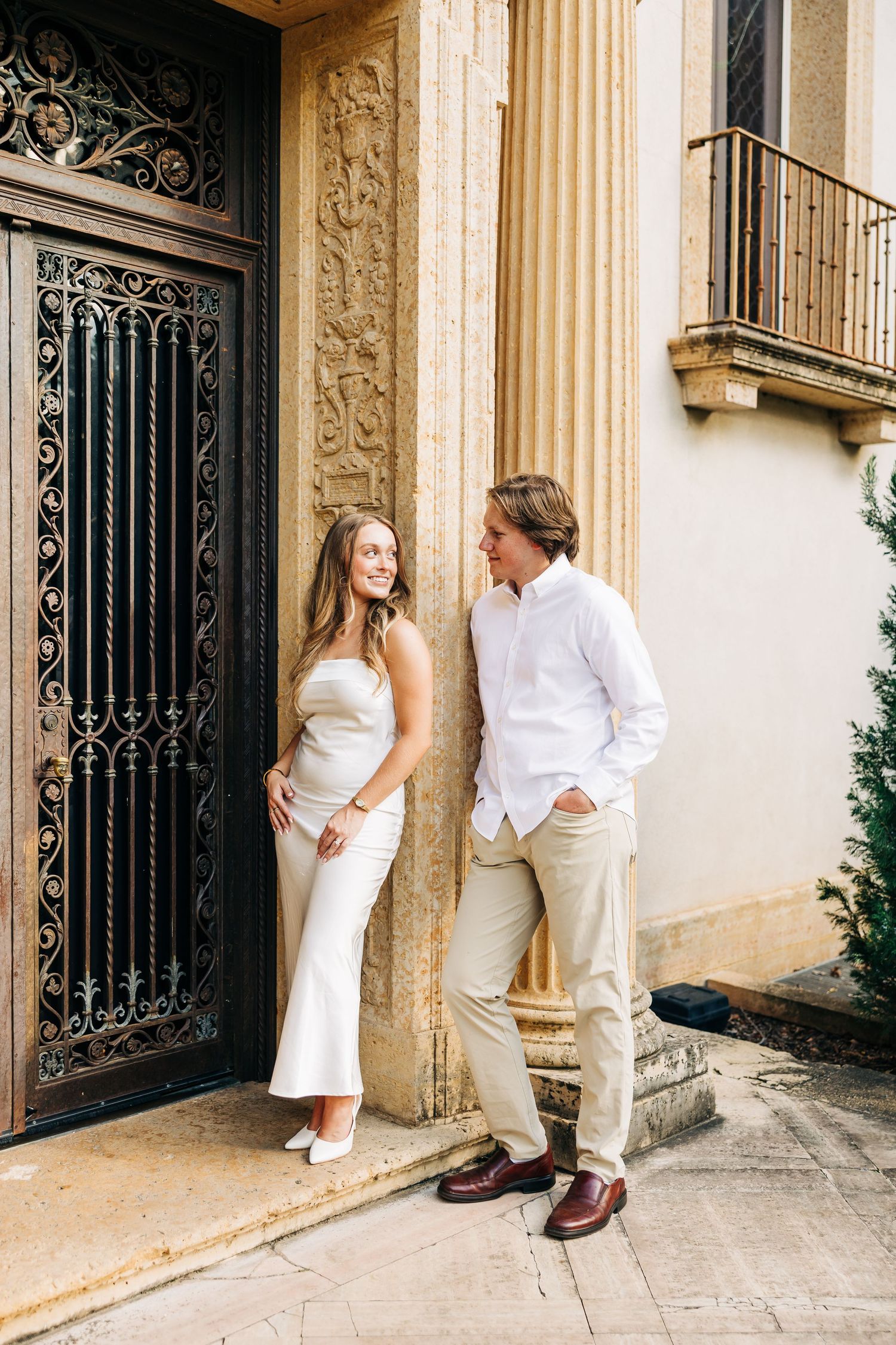 A sequence showing a couple in white clothing posing playfully against a classical stone building with columns.