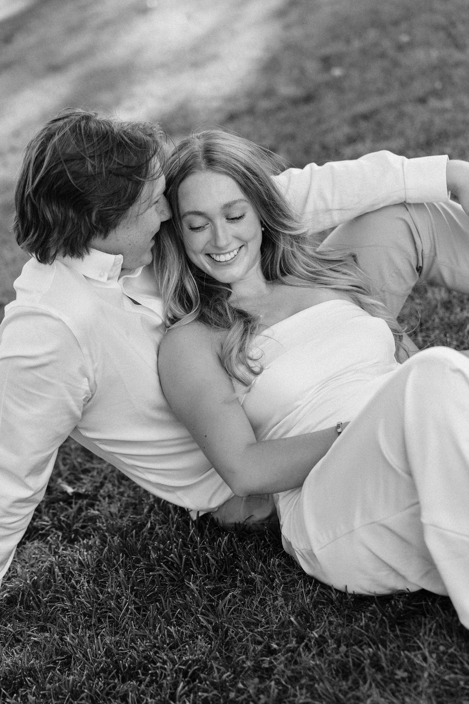 A romantic black and white photo sequence shows a couple in white clothing lying together on grass in tender moments.