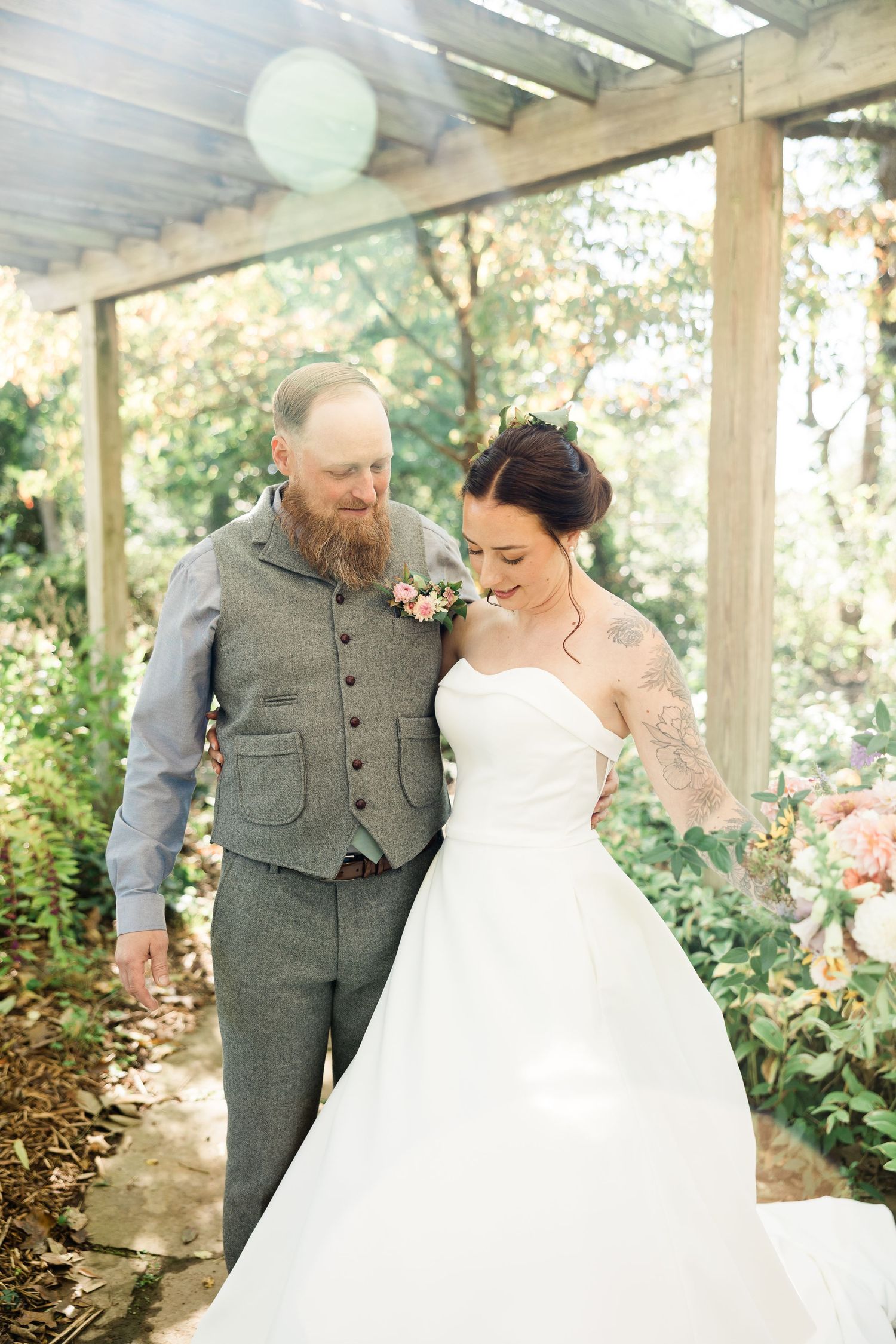 A romantic wedding couple embraces under a covered walkway with soft natural lighting.