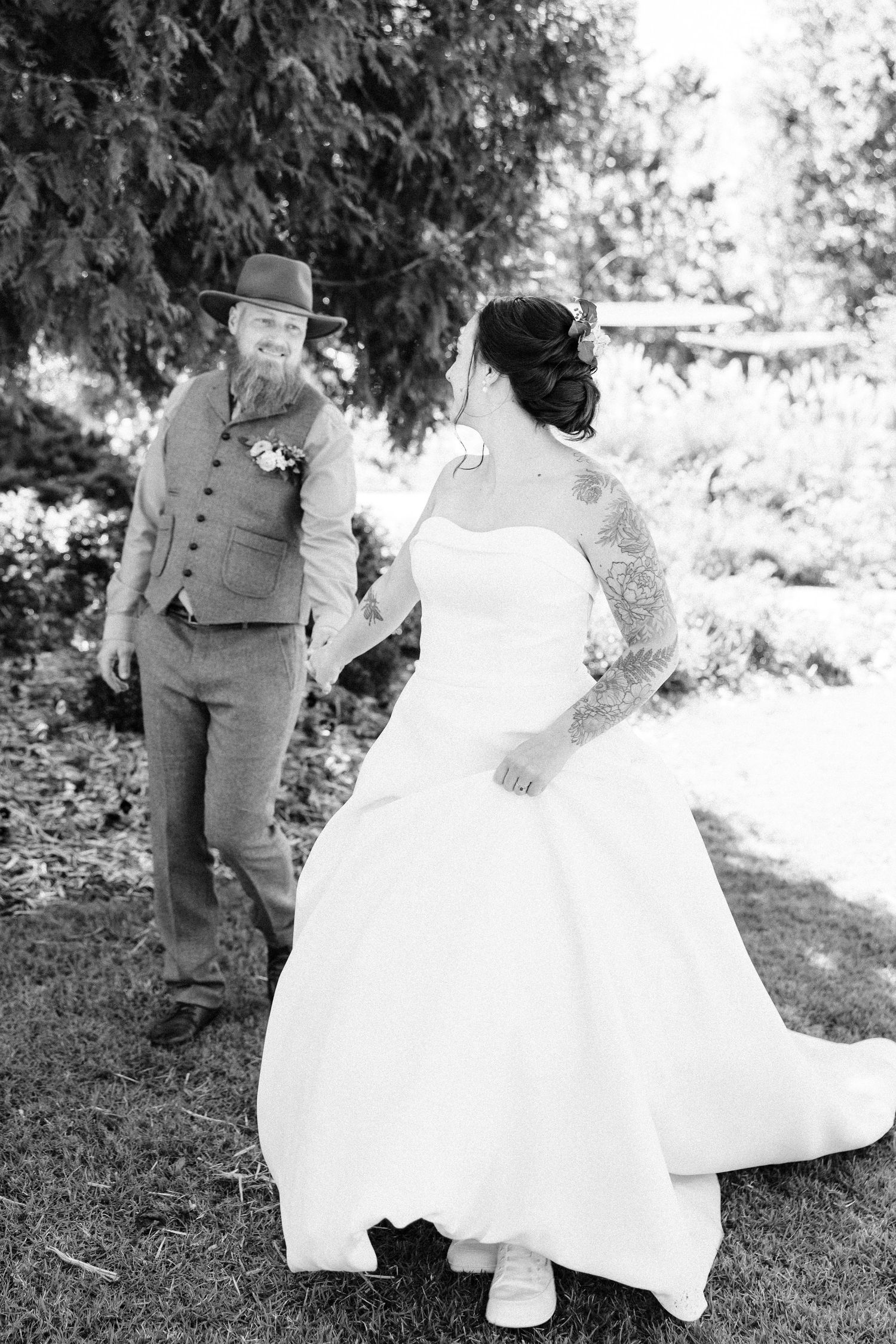 Wedding couple poses for artistic black and white photos in an outdoor garden setting.