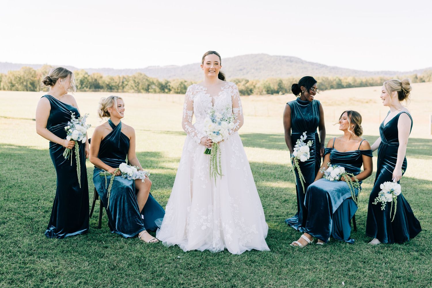 Wedding party gathered on a grassy lawn for formal group photos.
