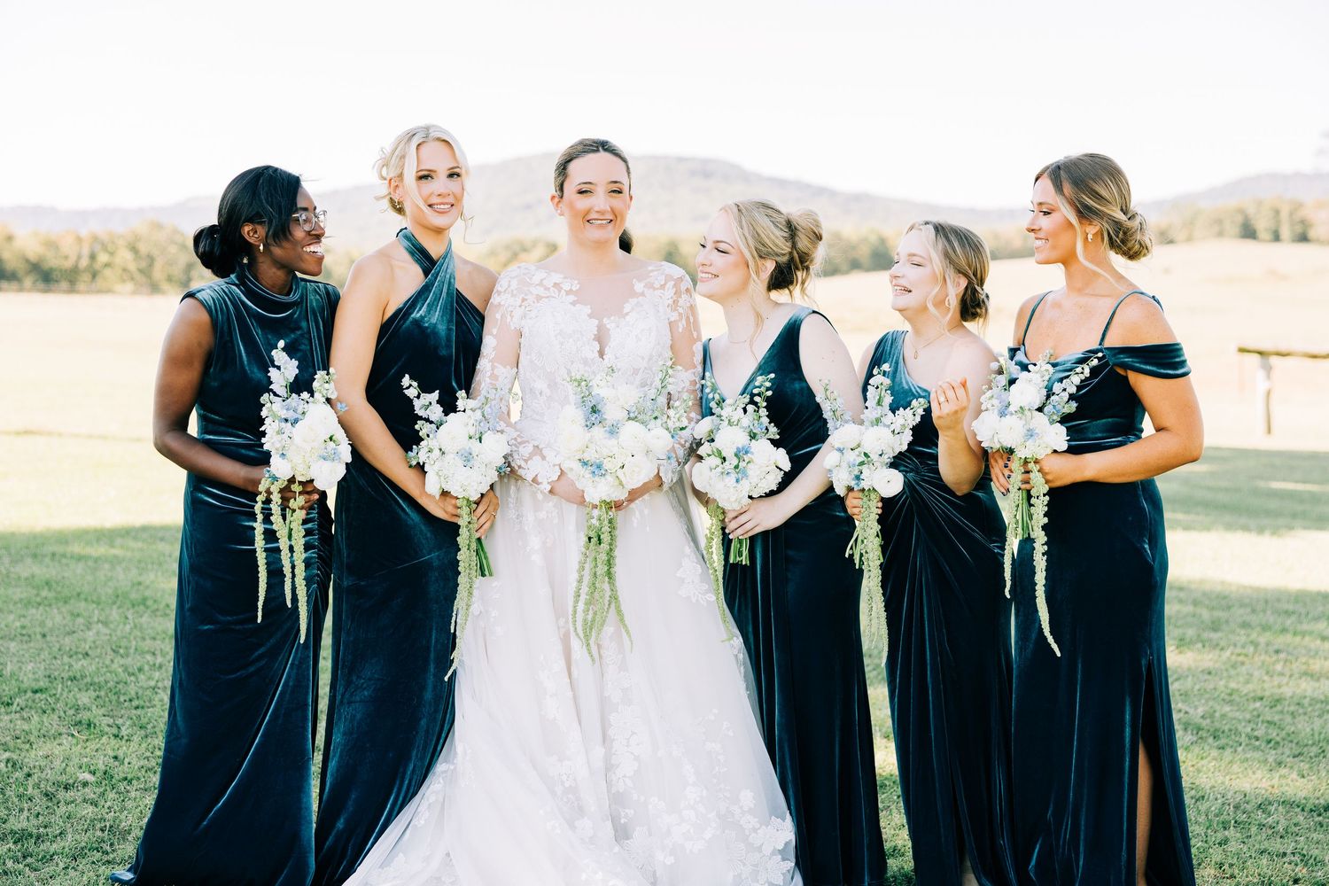 Wedding party in navy blue bridesmaid dresses and white bridal gown posing outdoors.