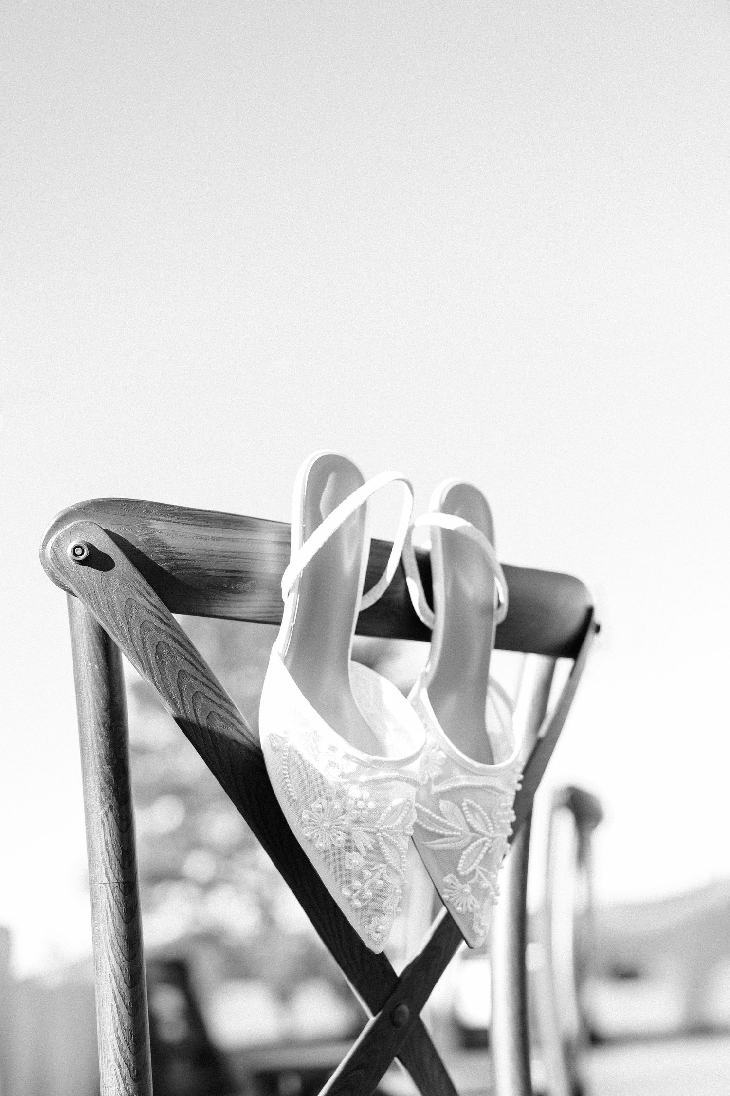 White wedding dress details hanging on rustic wooden hangers in soft light.
