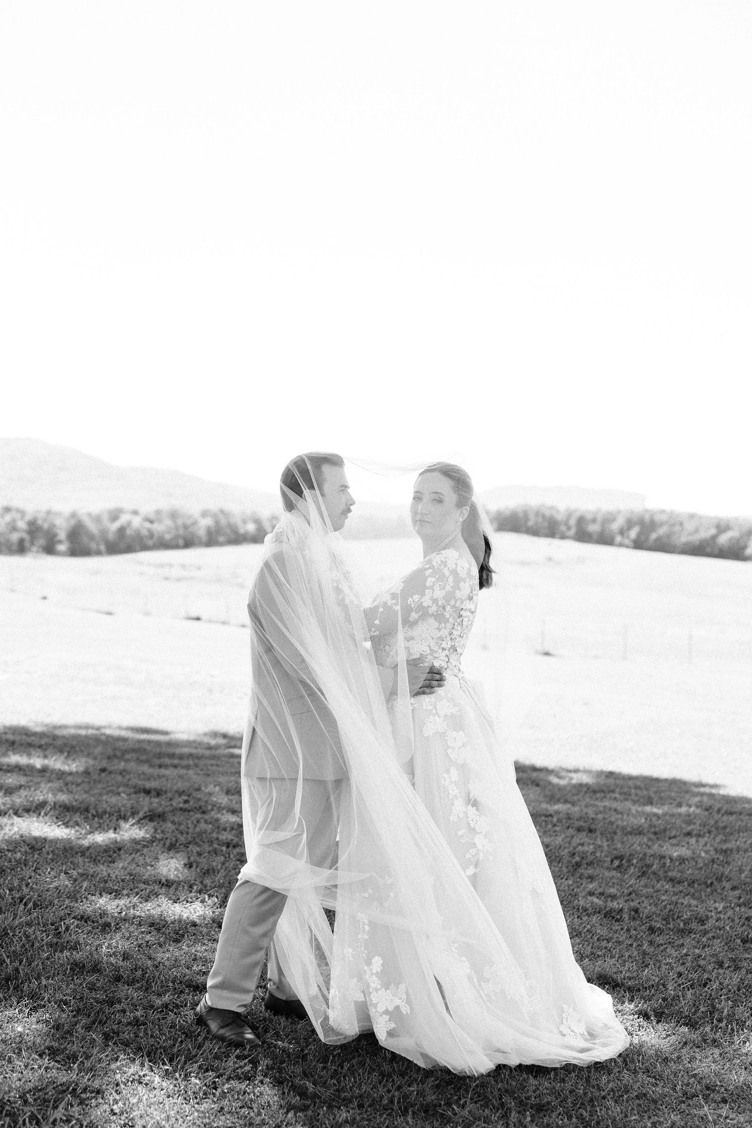Black and white panoramic sequence of a flowing white wedding dress in a grassy field.
