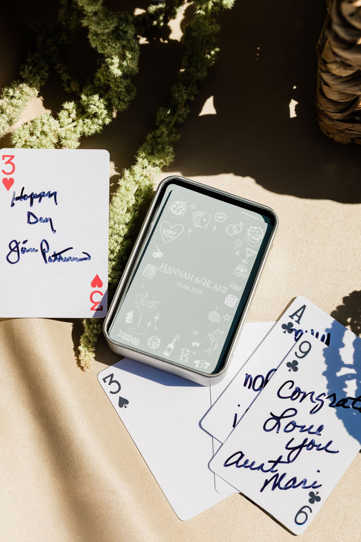 Playing cards scattered on a light surface with handwritten notes and signatures.