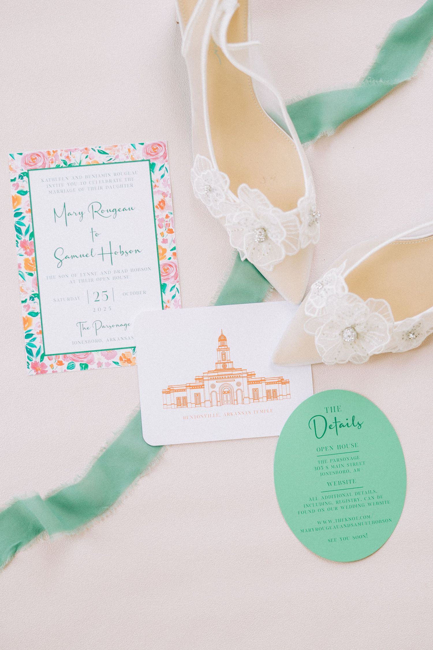 Wedding invitation suite featuring mint green and coral details with elegant white lace accessories.
