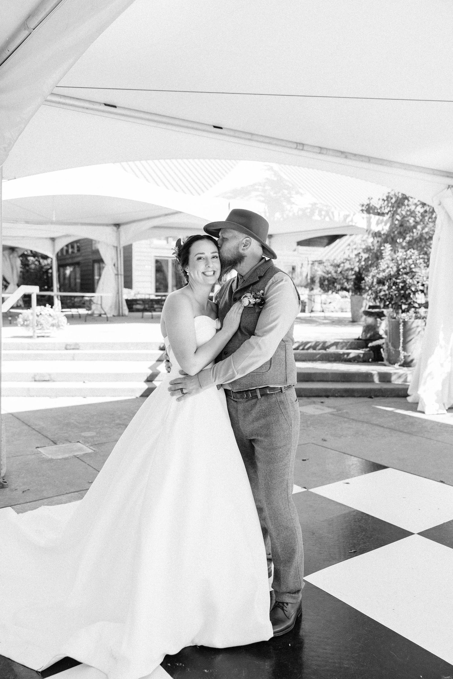 Wedding couple dances under a white tent during their outdoor reception celebration.