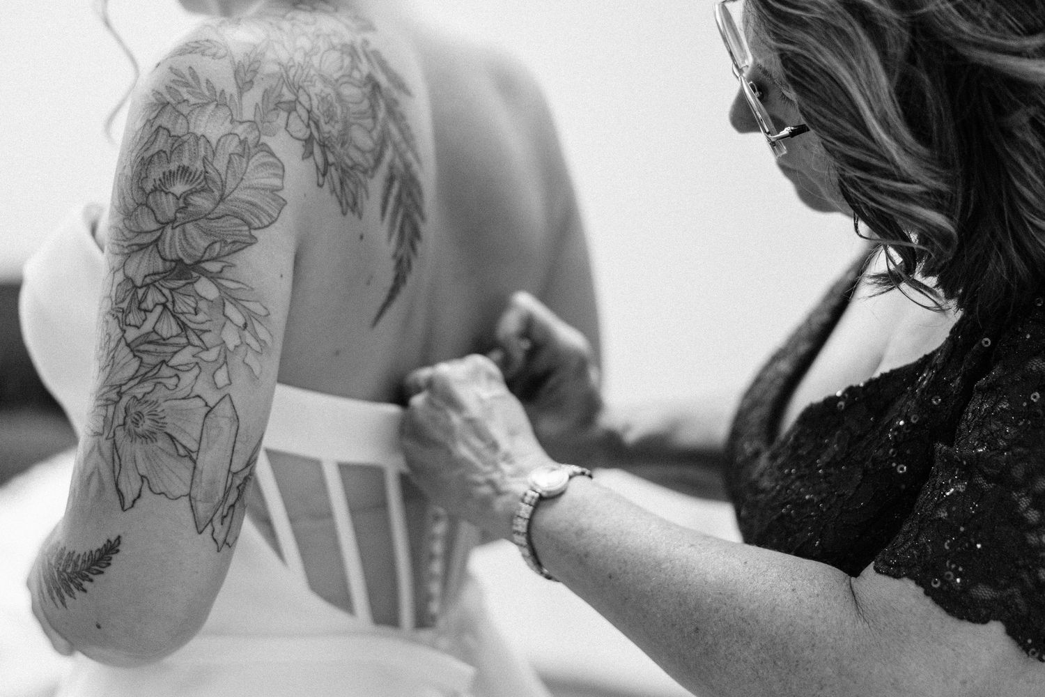 A black and white photo montage showing various stages of a tattoo artist working on a client's arm.