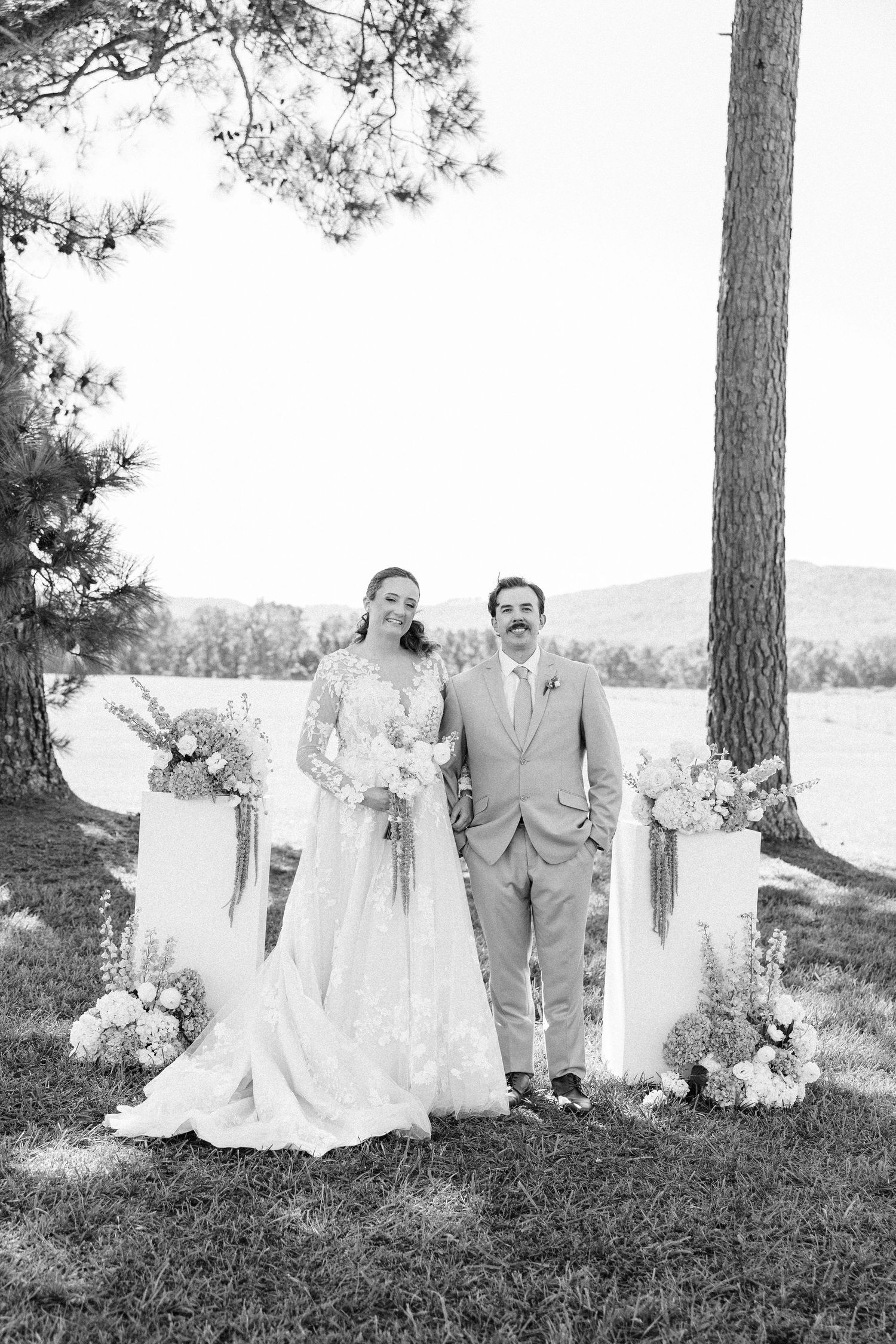 A romantic outdoor wedding photo series showing a couple and wedding party posing under tall pine trees.