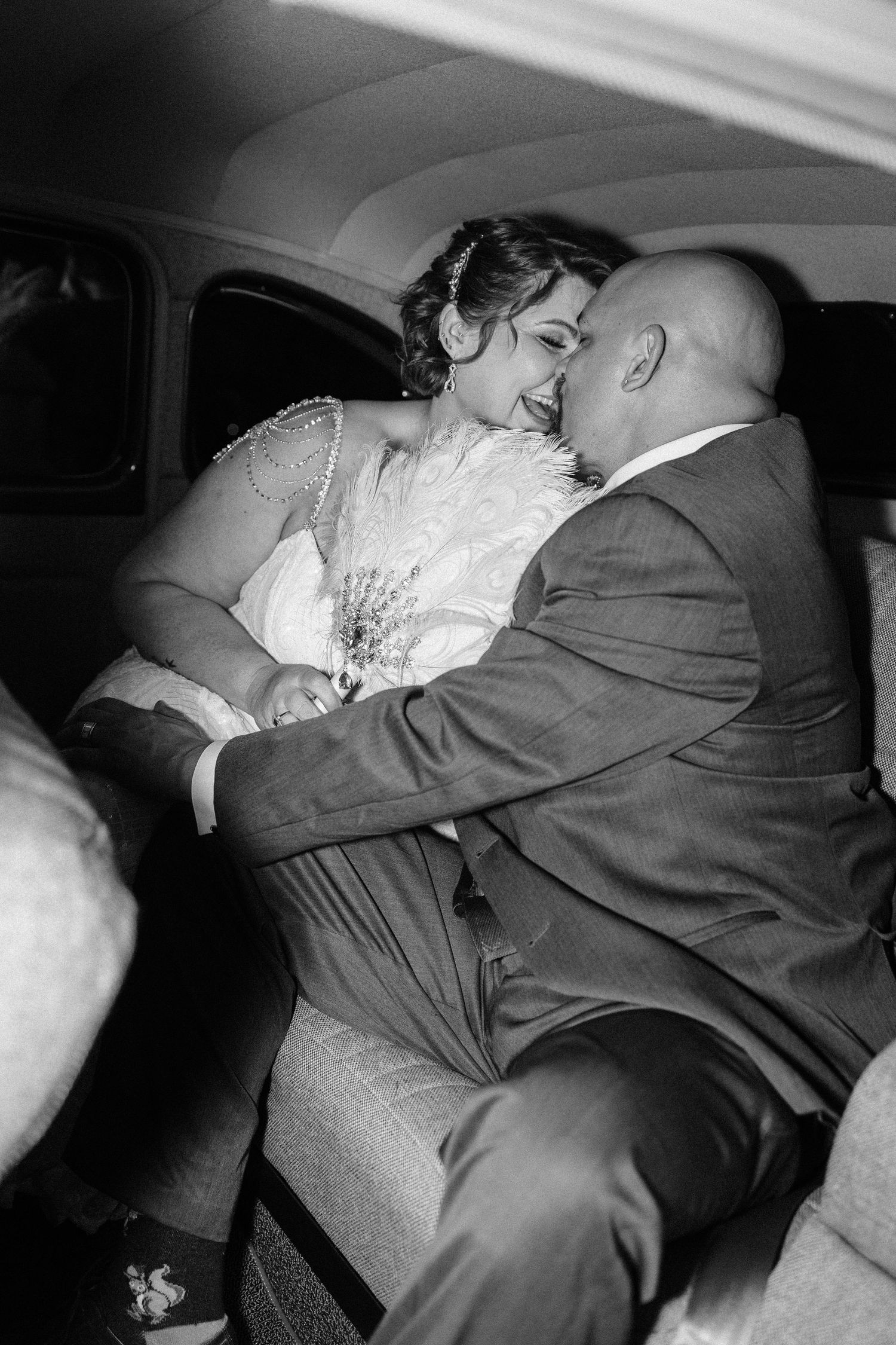 Intimate black and white sequence capturing tender moments between newlyweds in classic car.