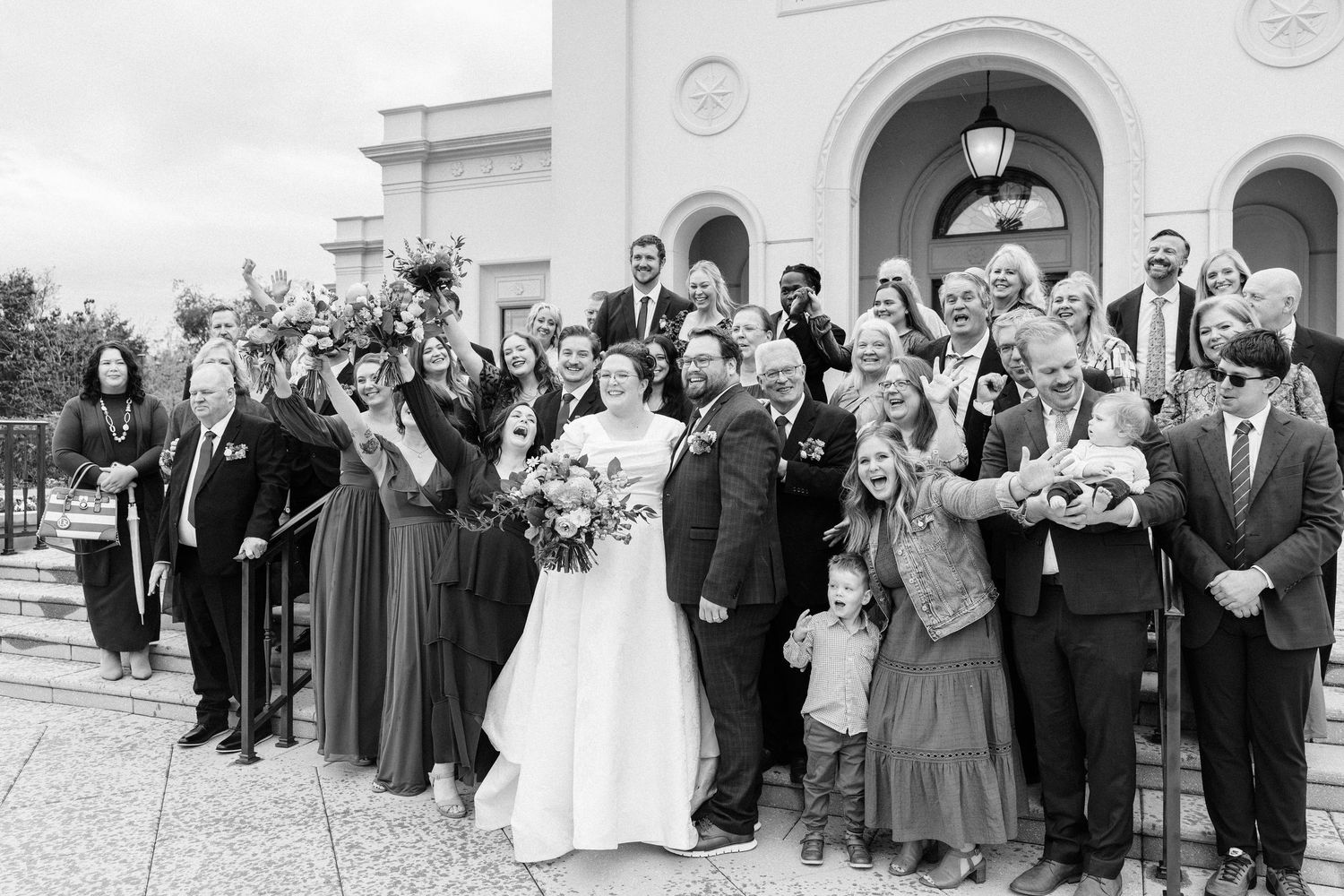A large wedding party gathered on church steps in black and white vintage photograph.
