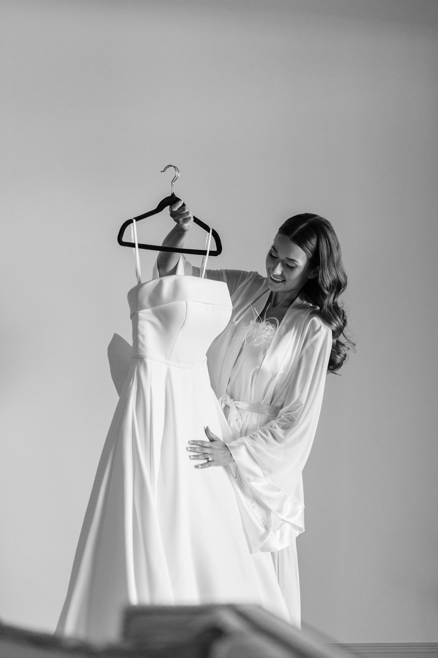A white wedding dress hangs on display as someone examines the details.