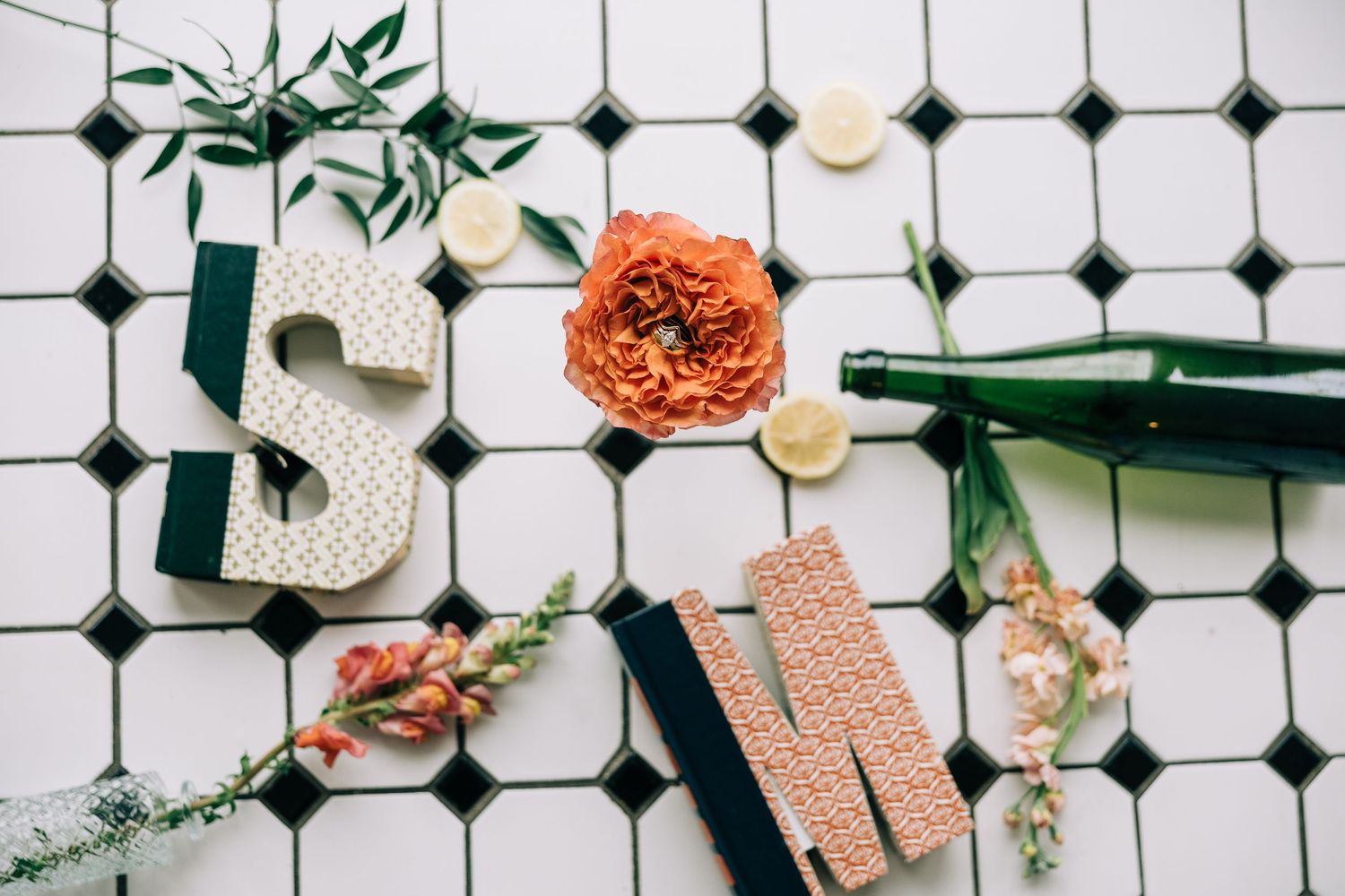 Overhead view of white and orange floral wedding decor elements on tiled surface.