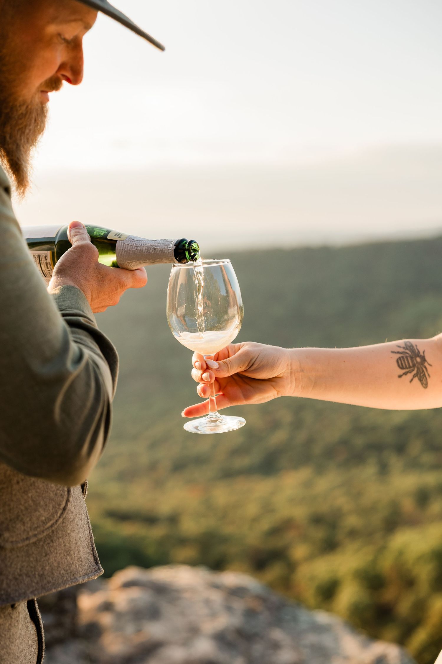 Close-up of wine glasses clinking during a sunset mountain wedding celebration.