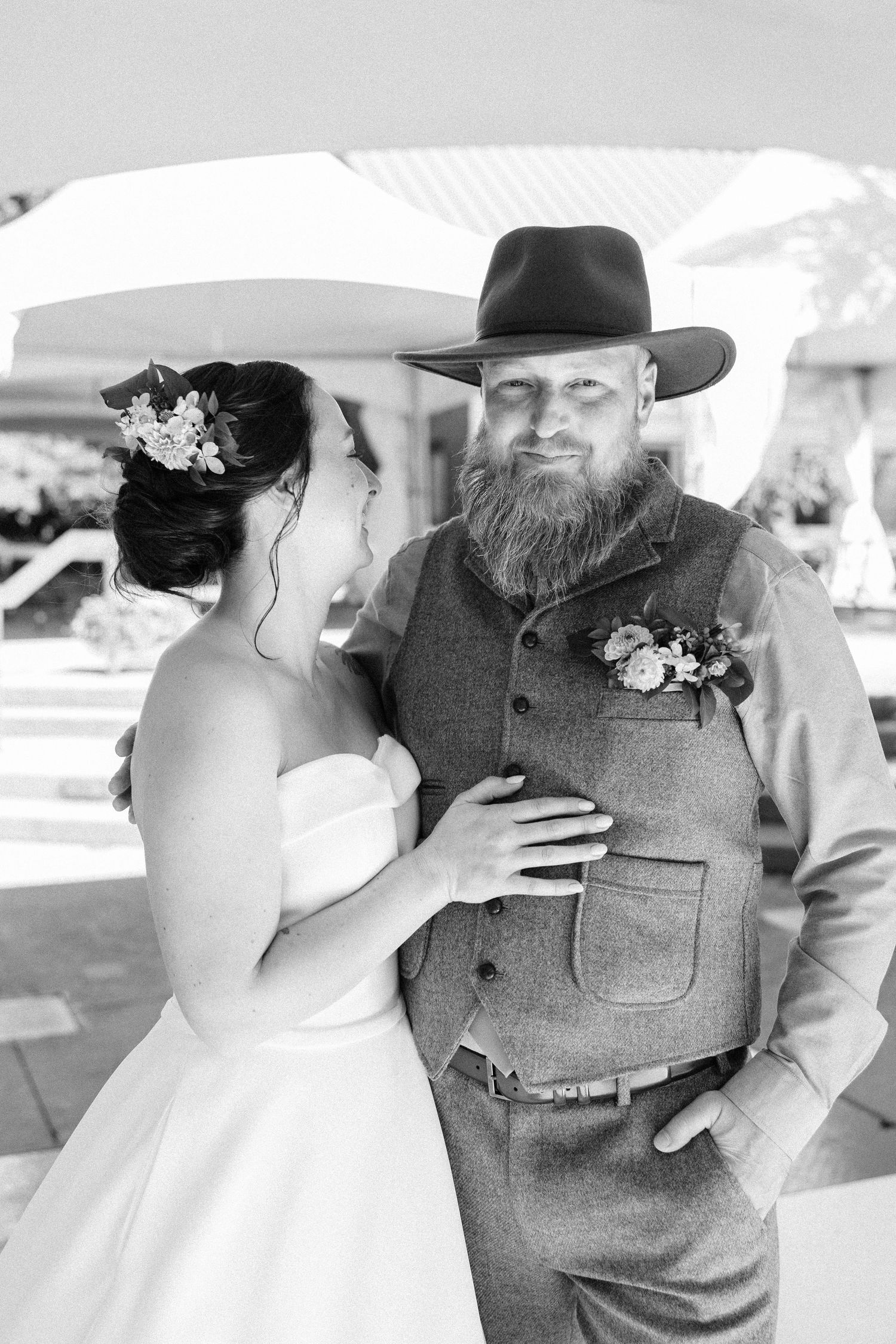 A black and white wedding portrait showing an intimate moment between newlyweds in western attire.