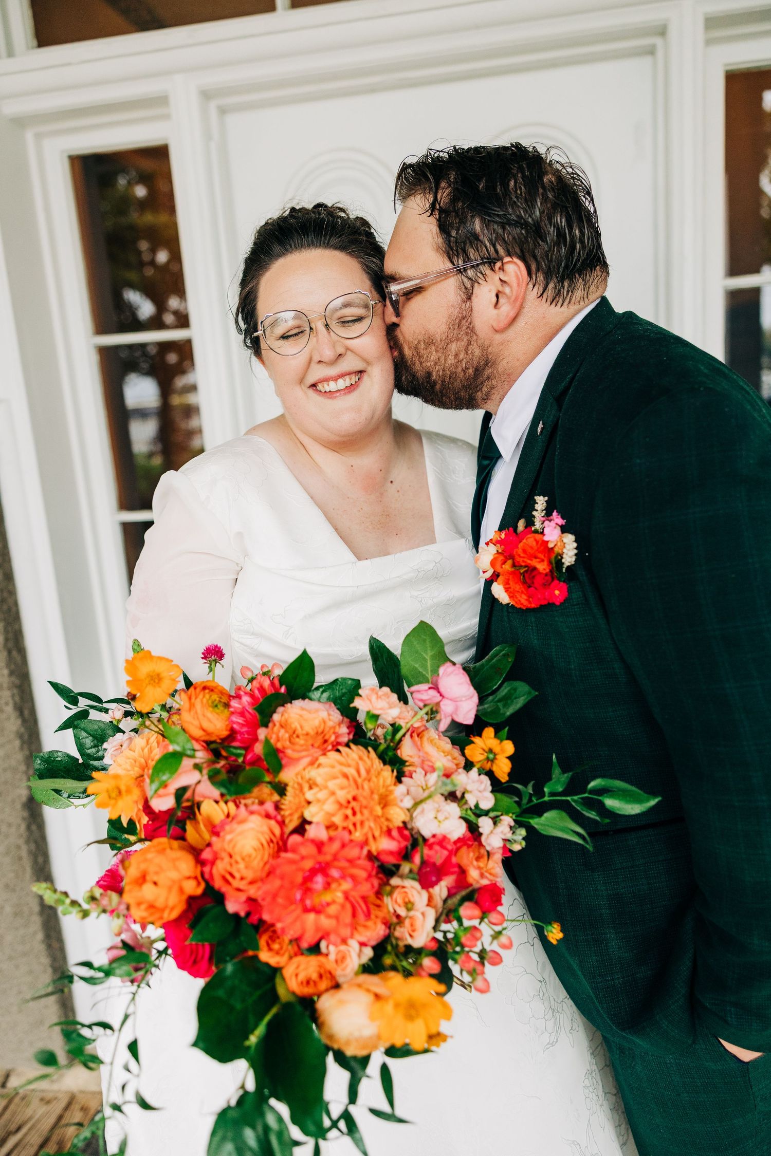 Vibrant orange and coral wedding bouquet with greenery displayed in a series of romantic wedding photos.