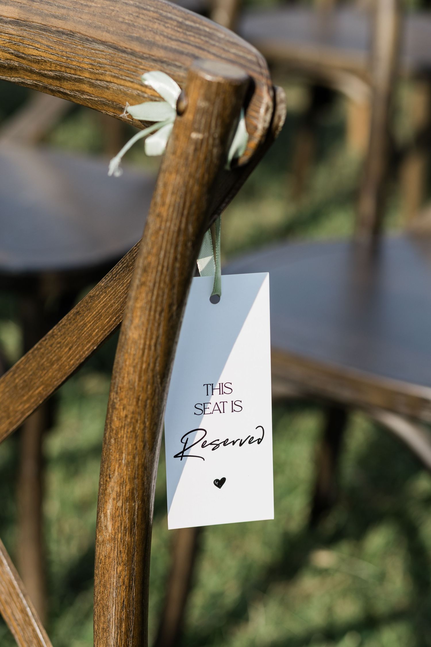 Small white paper tags with handwritten text hanging from rustic wooden beams in an outdoor setting.
